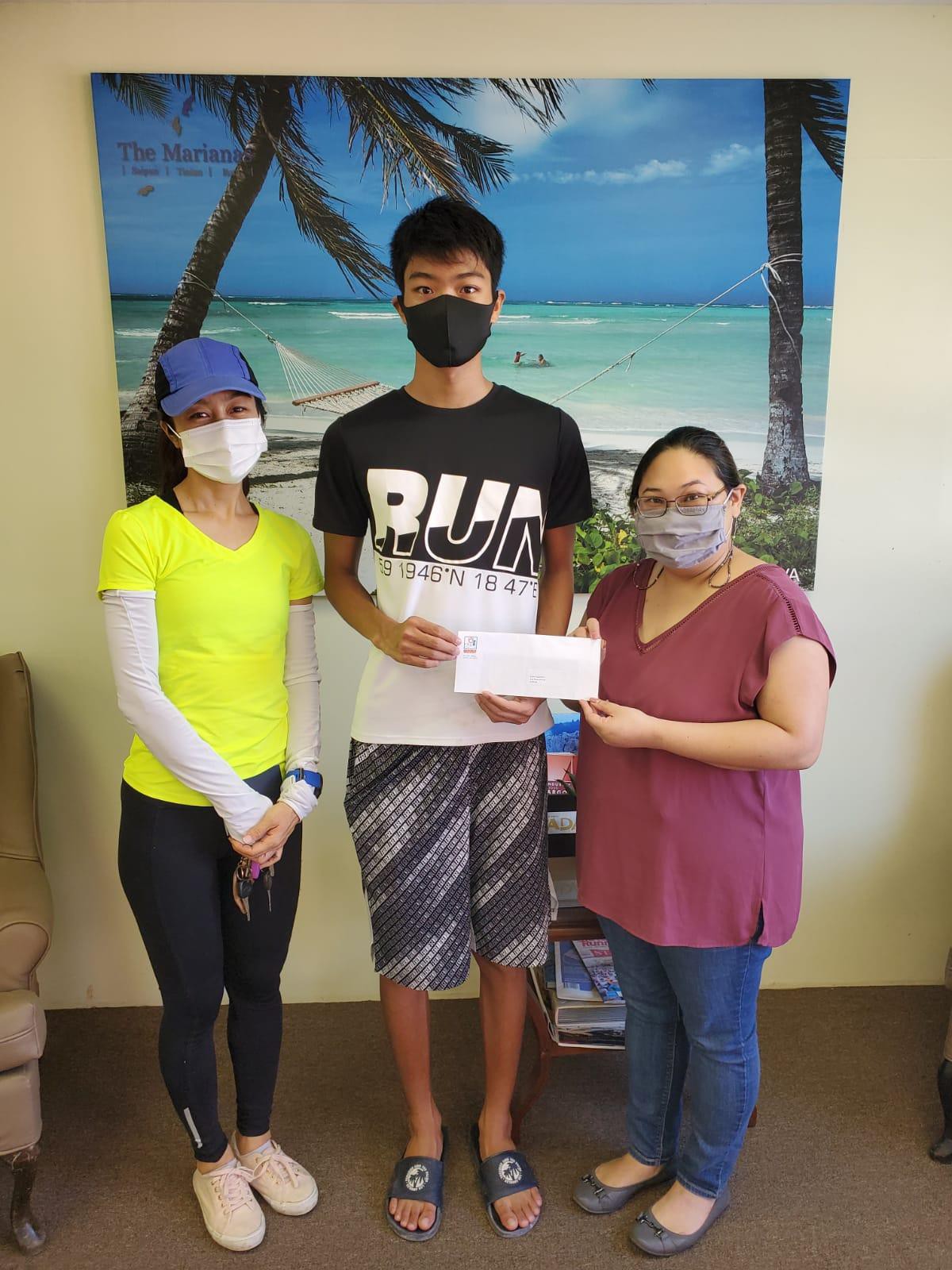 Rechucher  Kaito,  center,  is  awarded  2nd  place on June 4,  2021 in  the  Marianas Visitors  Authority's  Tourism Month essay contest.   From left,  his mother Yuki  Rechucher,  Rechucher Kaito, and MVA administrative  services  manager Carol  Chargualaf.