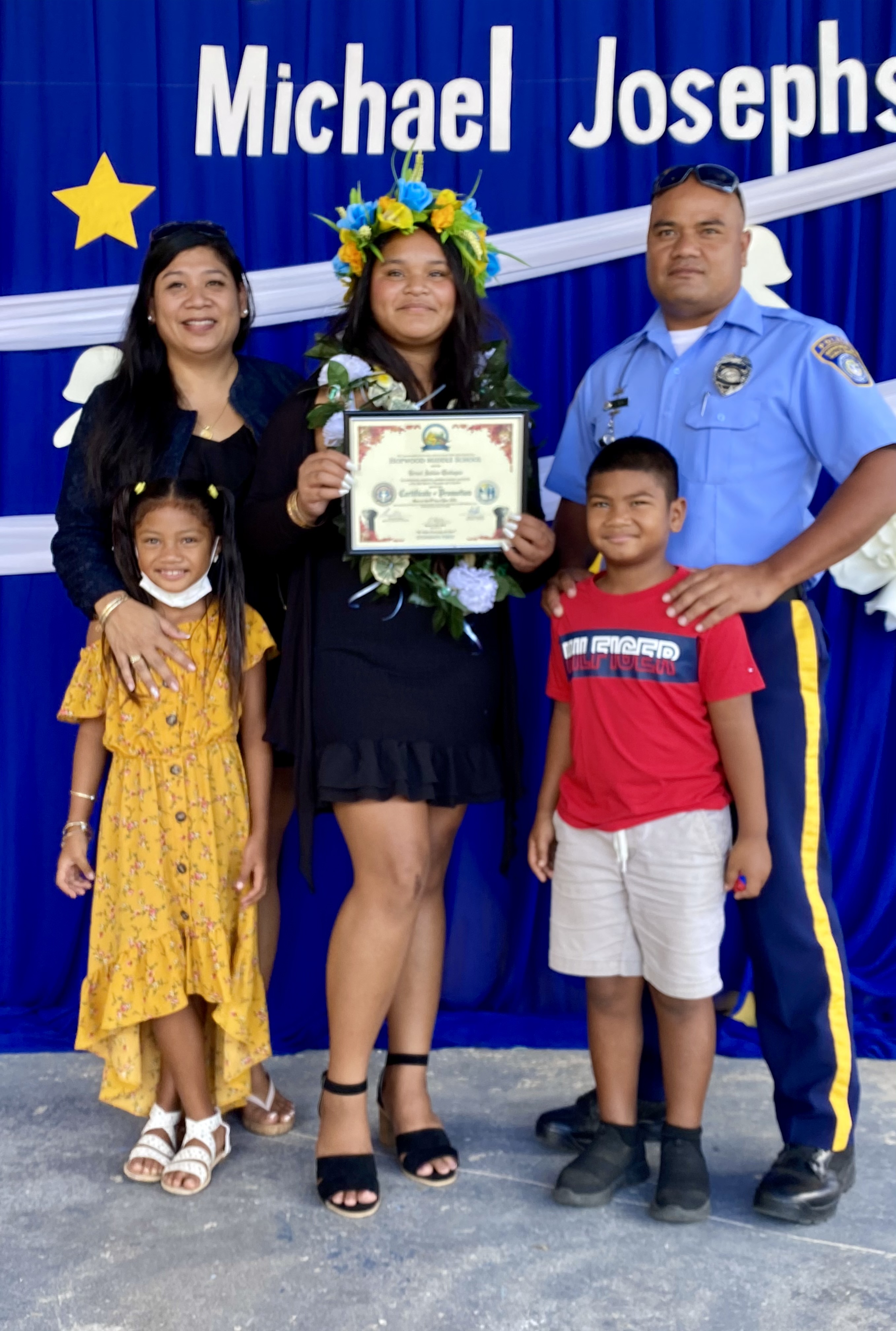 A newly promoted eighth grader poses with her proud parents and siblings.