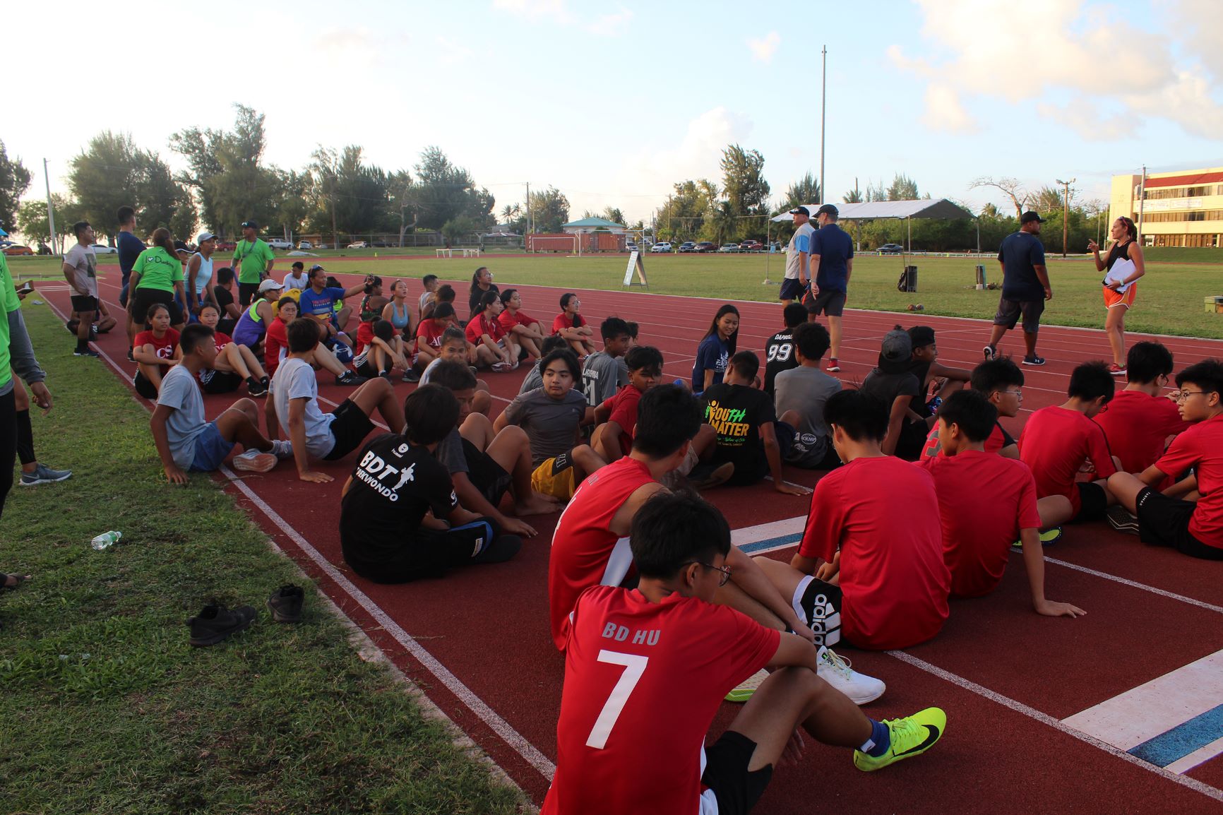 Young athletes gather on the track to watch the start of the 4 x 100 and Mixed Medley race.