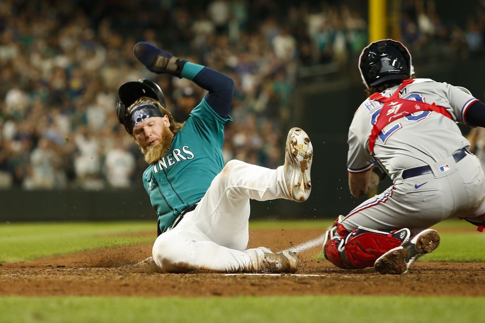Seattle Mariners left fielder Jake Fraley (28) slides homes to score a run against the Texas Rangers during the eighth inning at T-Mobile Park in Seattle, Washington, July 2, 2021.