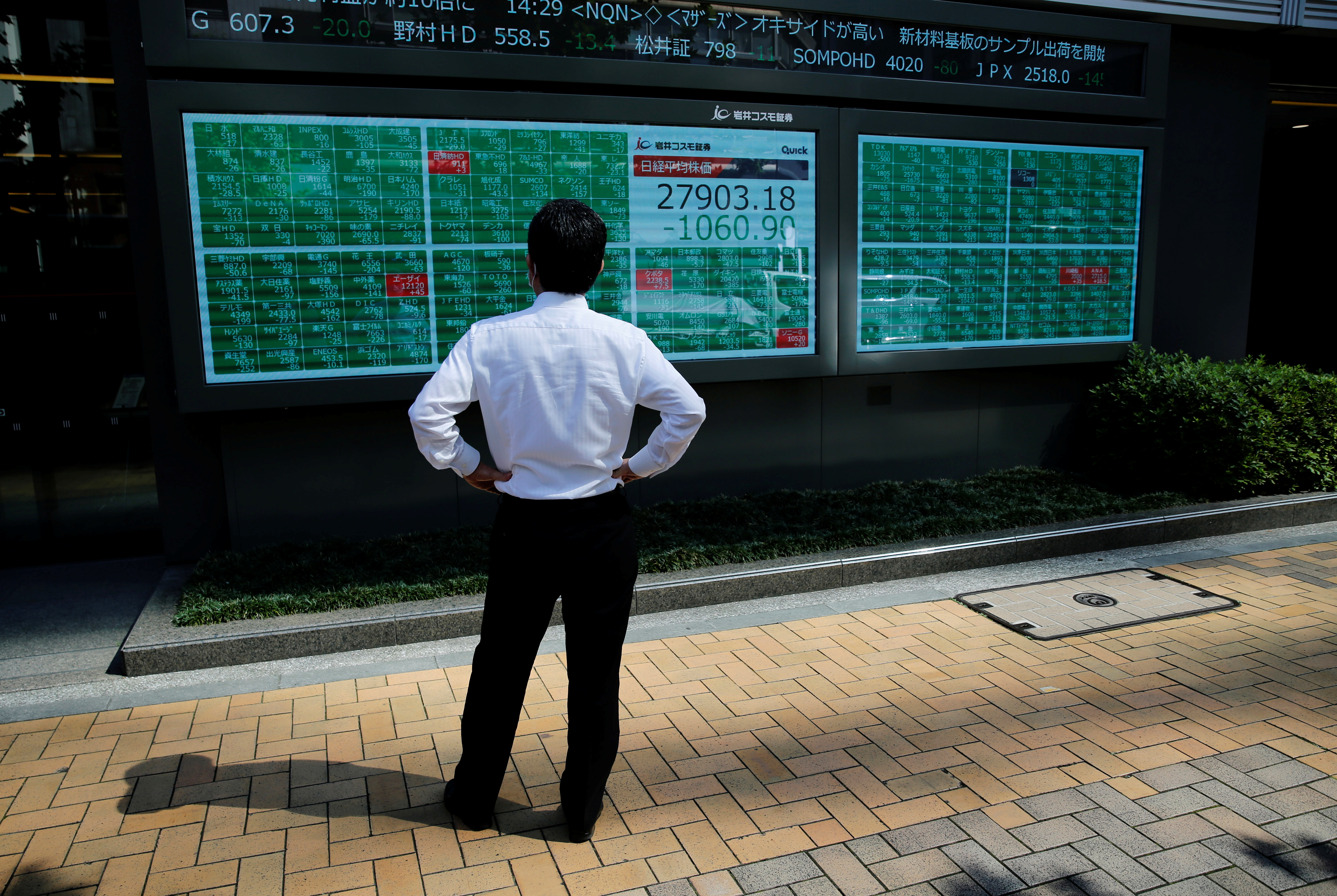 A man watches an electric board showing Nikkei index outside a brokerage at a business district in Tokyo, Japan on June 21, 2021.