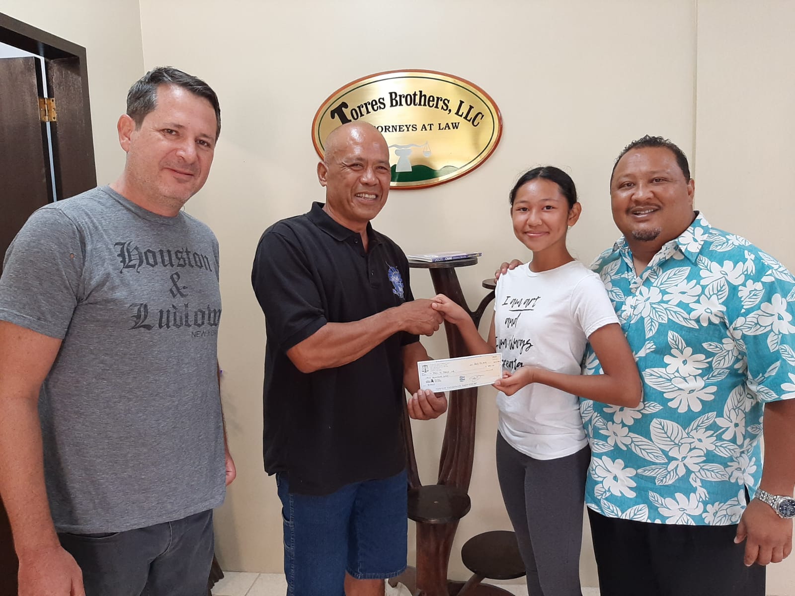 Torres Brothers LLC's Matt Holley, Jacqueline T. Torres, and Jack Torres donate a check for $500 to Tasi To Table’s Gene Weaver.