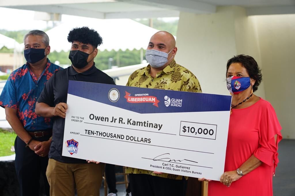 Owen Kamtinay, second left, holds a ceremonial check representing the $10,000 grand prize he won during the Vax N’ Win raffle draw at the Ricardo J. Bordallo Governor’s Complex in Adelup on Wednesday morning.