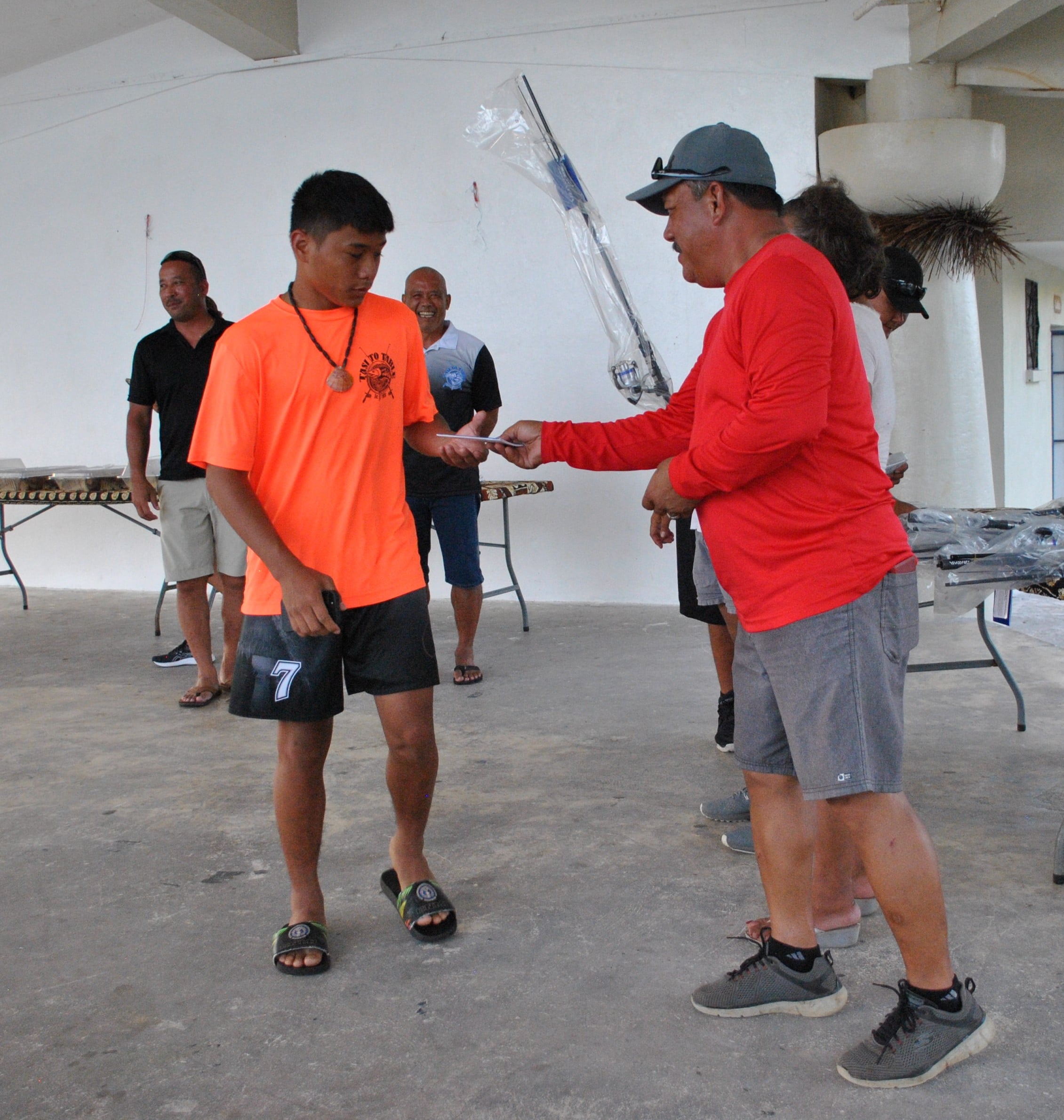 Tinian Mayor of Tinian Edwin P. Aldan hands a gift certificate to one of the high school students who also received a rod and reel combo from Tasi To Table.