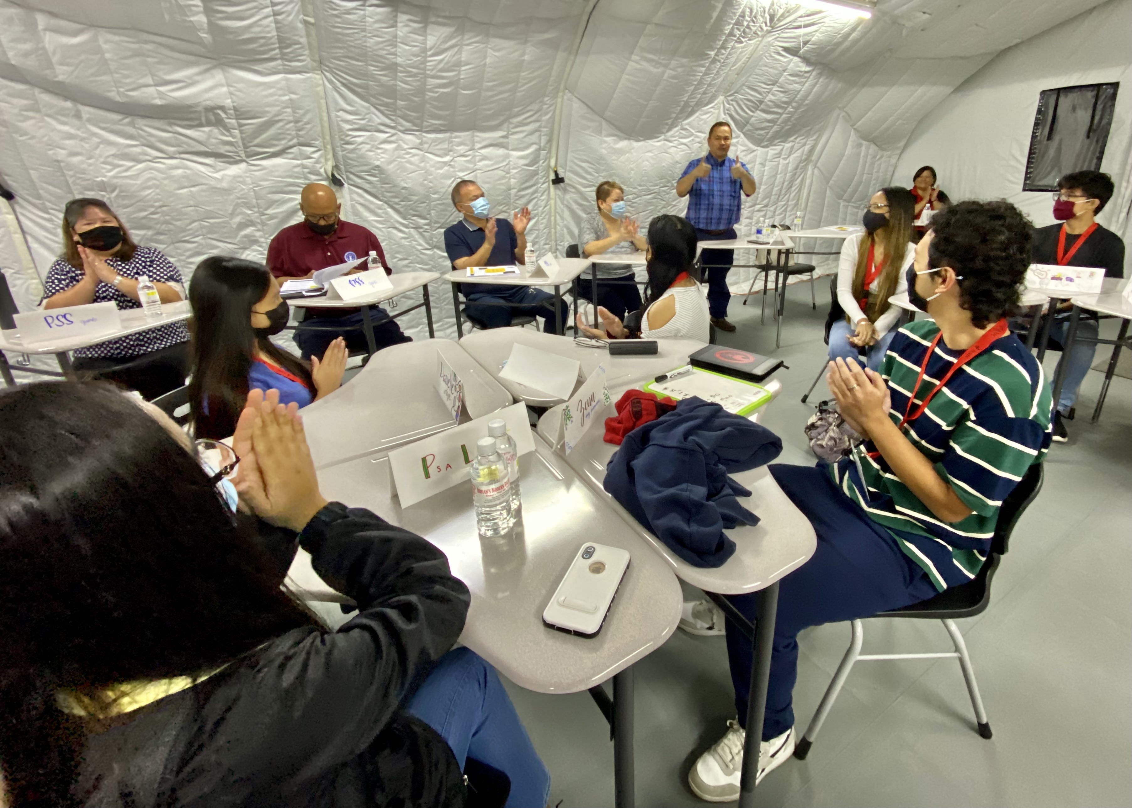 Commissioner of Education Dr. Ada, standing, gestures as he congratulates the participating students.