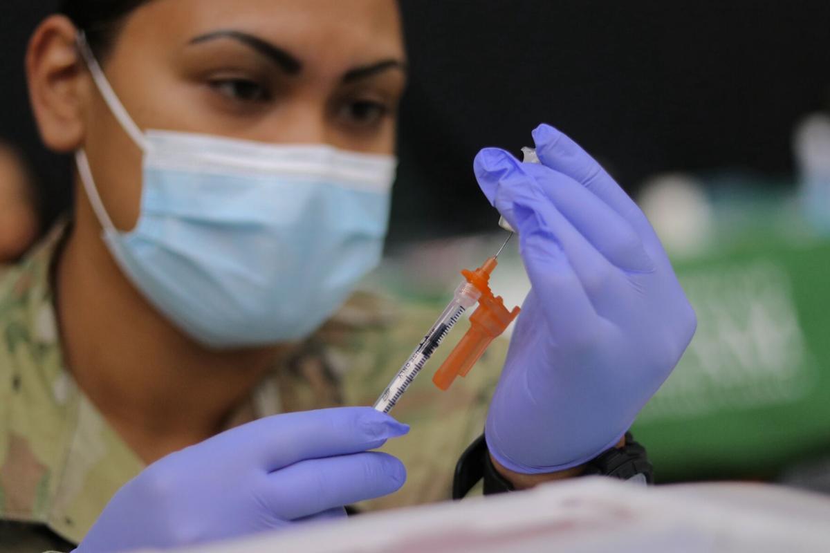 Guam Army National Guard Medic SPC. Heather Nera prepares jabs of the Pfizer Covid-19 vaccine to be administered at the University of Guam Calvo Field House on Friday.