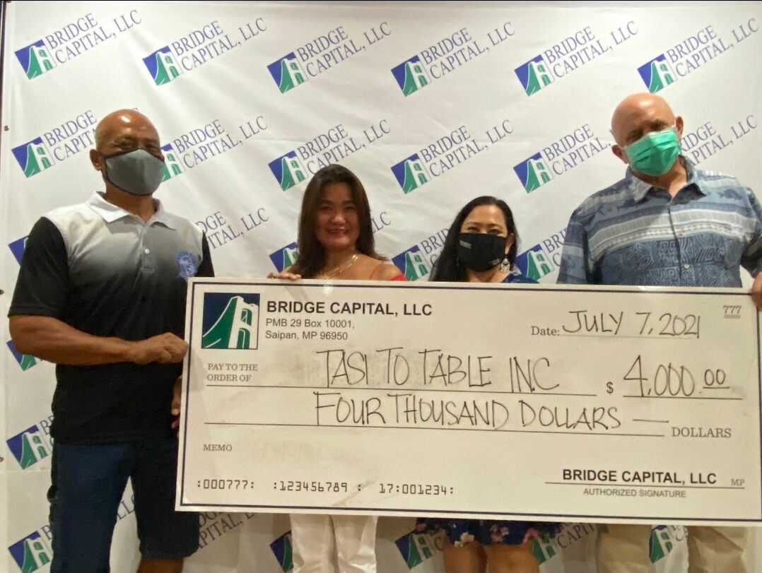 Tasi To Table’s Gene Weaver and Normie Cania hold a ceremonial check for $4,000 with  Bridge Capital's Julie Duenas and Bart Jackson.