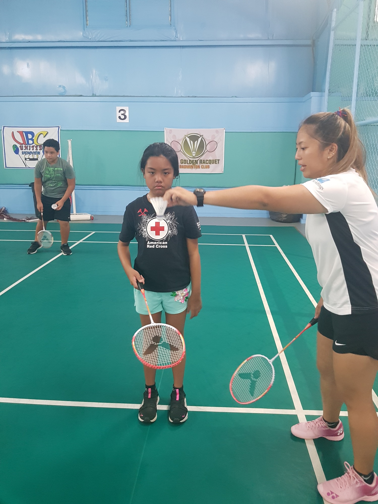 Northern Marianas Badminton Association director Janelle Pangilinan assists a camp participant.