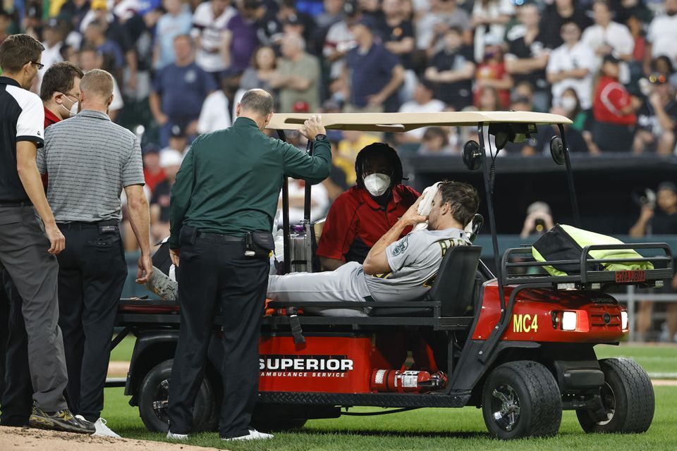 Medical personnel helps Oakland Athletics starting pitcher Chris Bassitt (40) who covers his face after being hit by a ball hit by Chicago White Sox left fielder Brian Goodwin during the second inning at Guaranteed Rate Field in Chicago, Illinois on Aug. 17, 2021.