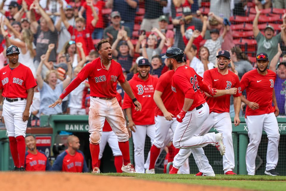 Boston Red Sox shortstop Xander Bogaerts (2) celebrates with Boston Red Sox first baseman Travis Shaw (23) after Shaw hit a game winning grand slam during the 11th inning against the Texas Rangers at Fenway Park in Boston on Aug. 23, 2021.