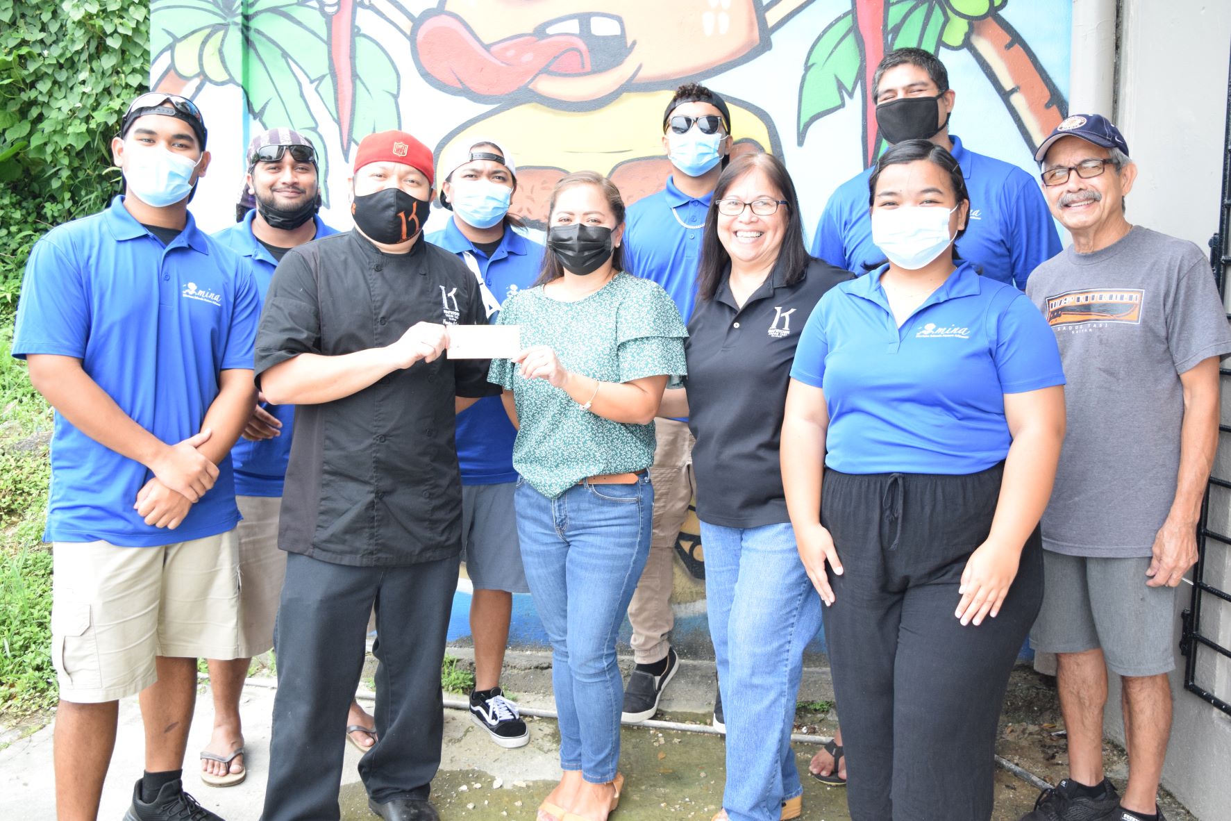 Inas' Kitchen Chef Sonnie Sablan, third left, presents a check donation to Micronesia Islands Nature Alliance Program Director Becky Furey, center. Also in the photo are Inas’ Kitchen owners, Frank, right and Rita A. Sablan, third right, and Tasi Watch community rangers.