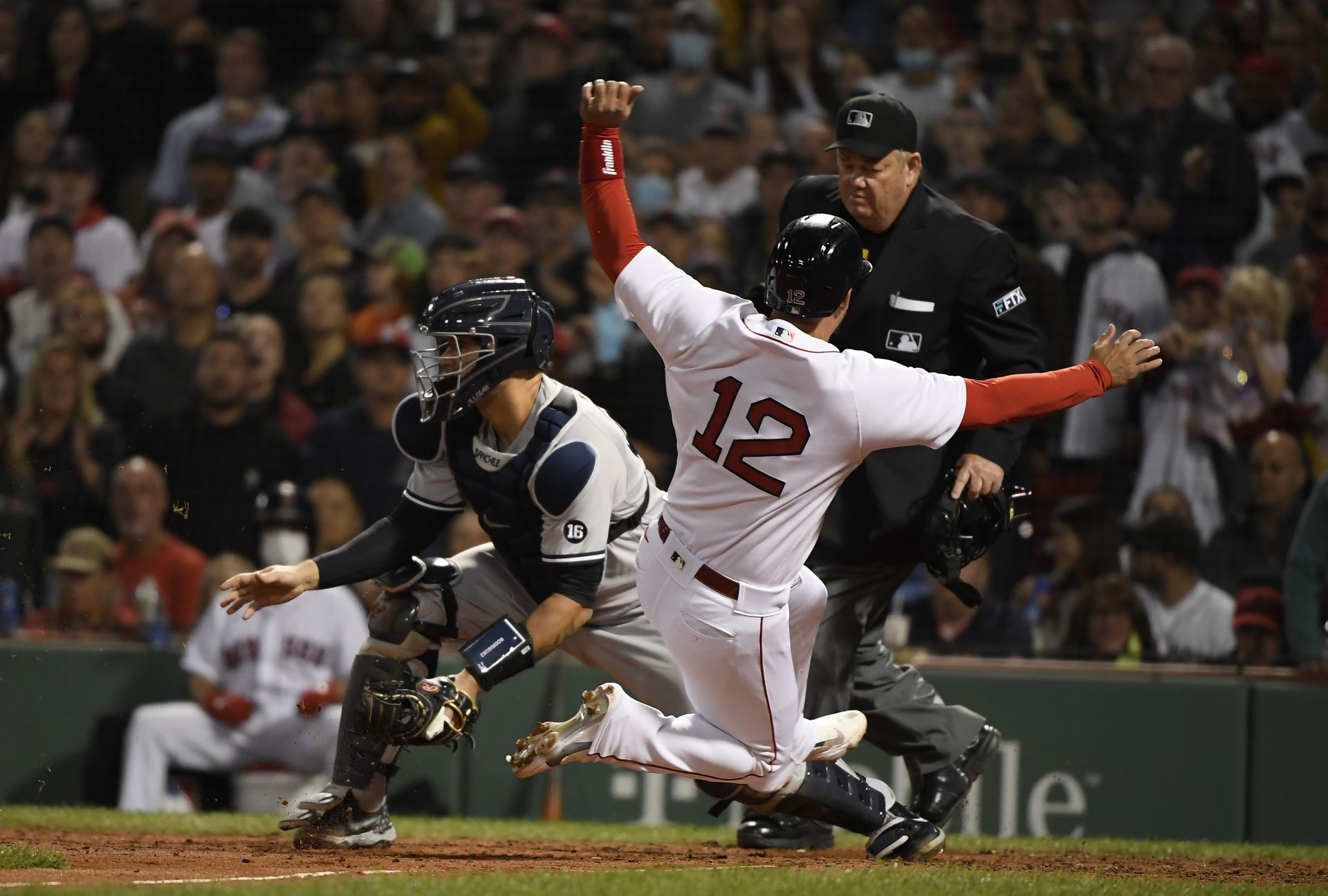 Boston Red Sox pinch hitter Jose Iglesias (12) slides safely into home past New York Yankees catcher Gary Sanchez (24) during the seventh inning at Fenway Park in Boston on Sept. 26, 2021.