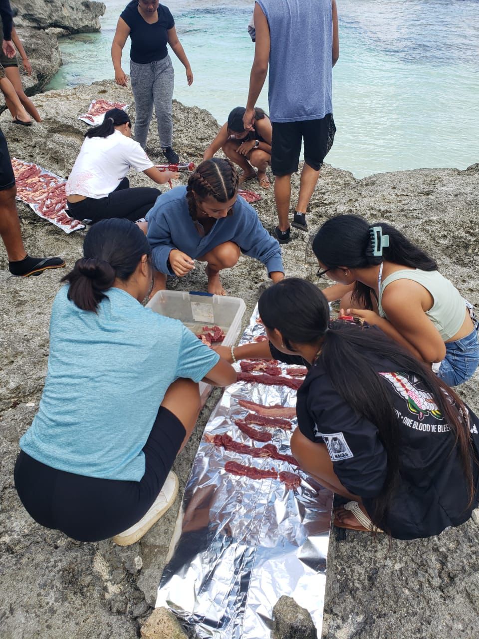 The famalao'an work together to lay out cuts of the cow meat to “tala” on the rocks, Rota Style, at Swimming Hole.