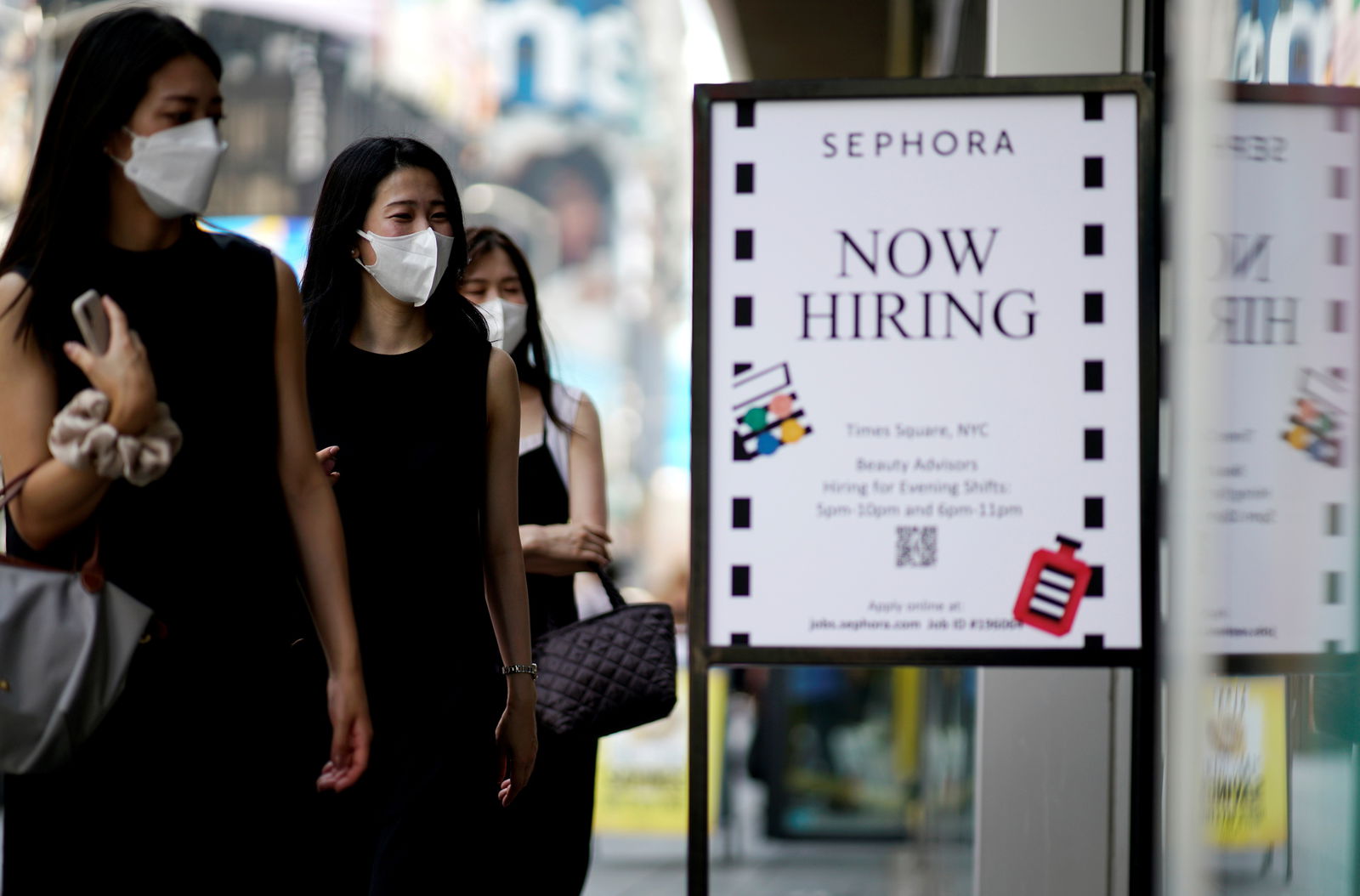 A sign advertising job openings is seen while people walk into the store in New York City, New York on Aug. 6, 2021.
