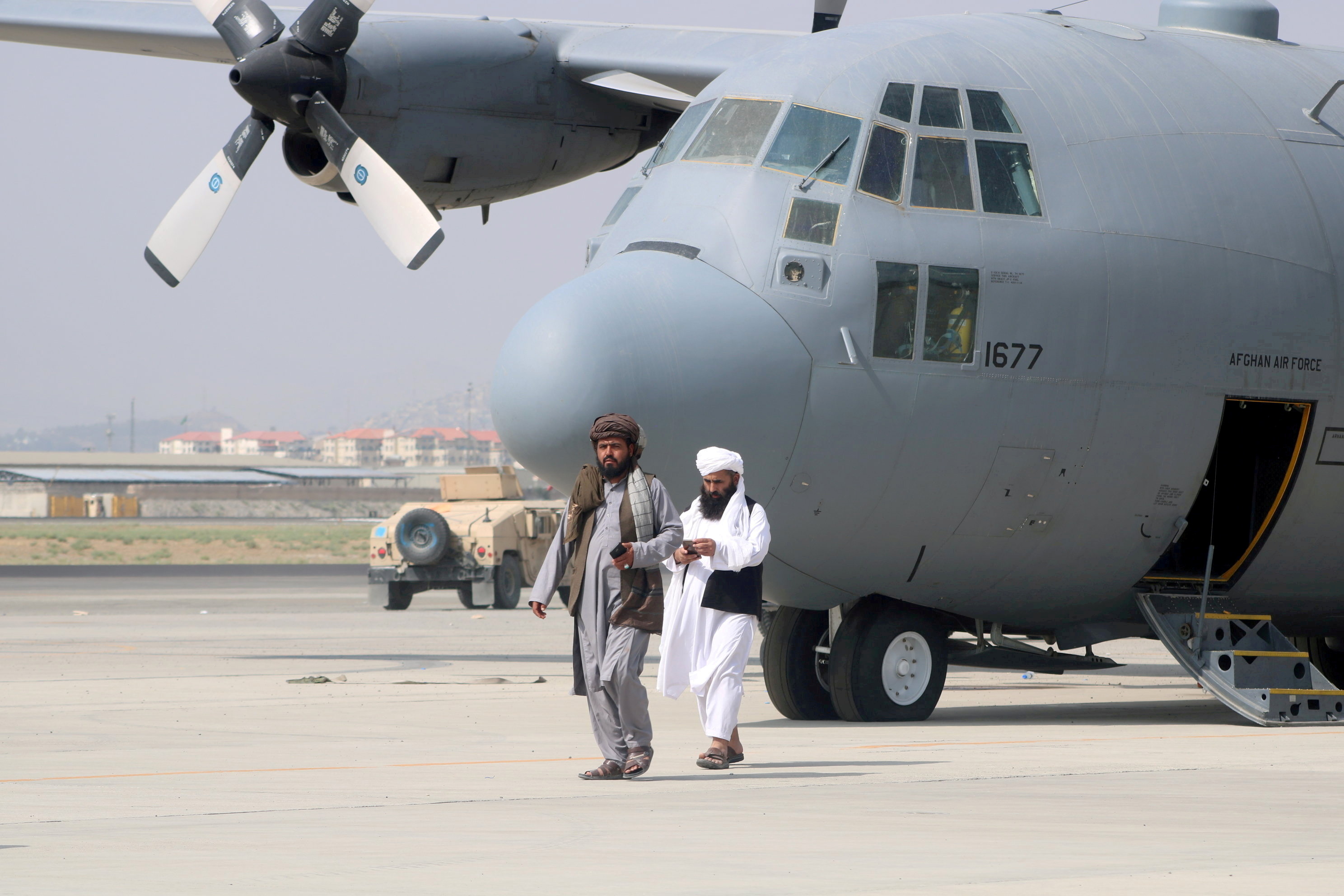 Taliban fighters walk in front of a military airplane a day after the U.S. troops withdrawal from Hamid Karzai International Airport in Kabul, Afghanistan on Aug. 31, 2021.