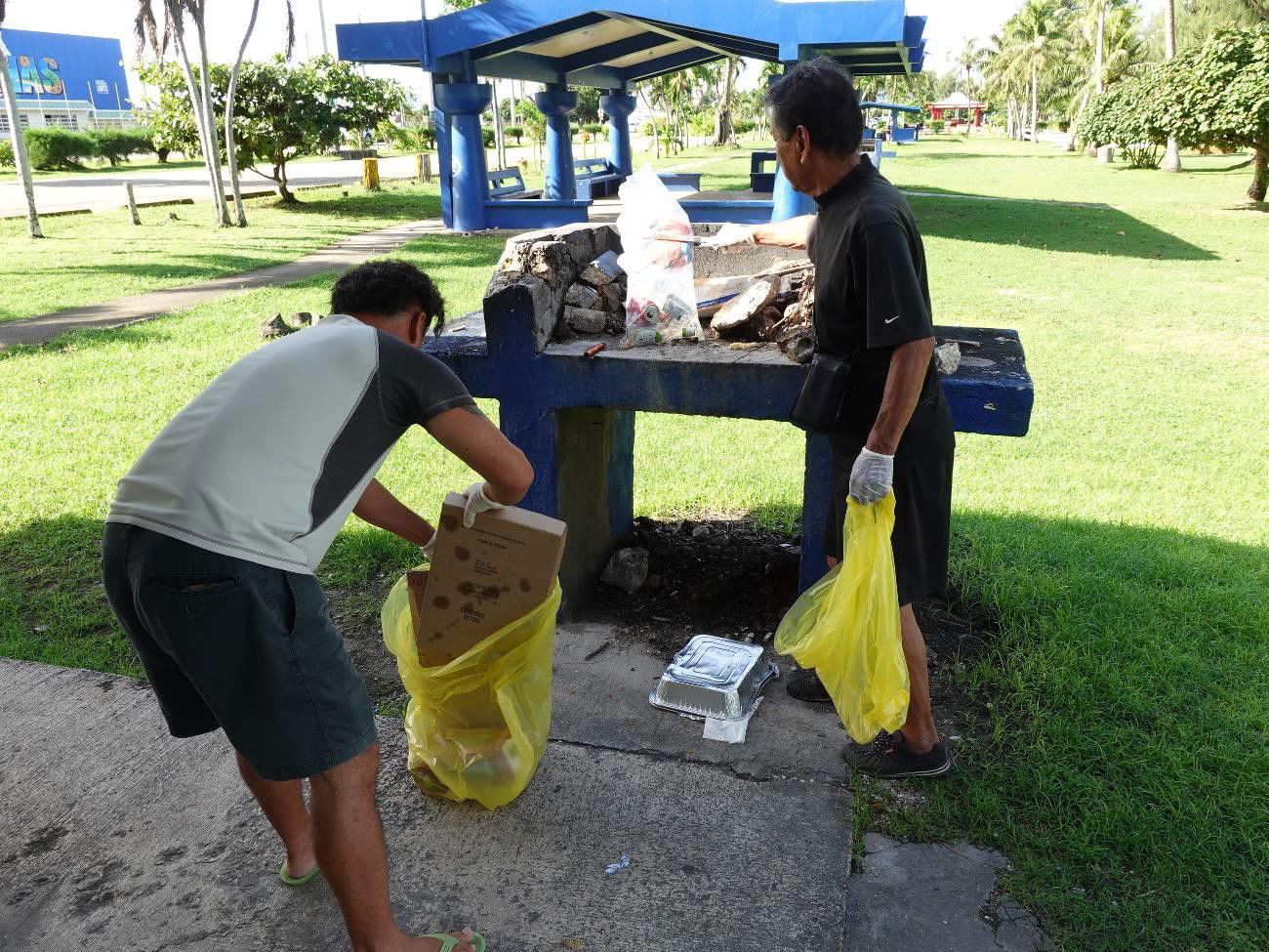 Hitoshi Yamaguchi, left, and Seiji Sato participate in a beach cleanup in Saipan on Sept. 27, 2021, in celebration of World Tourism Day.