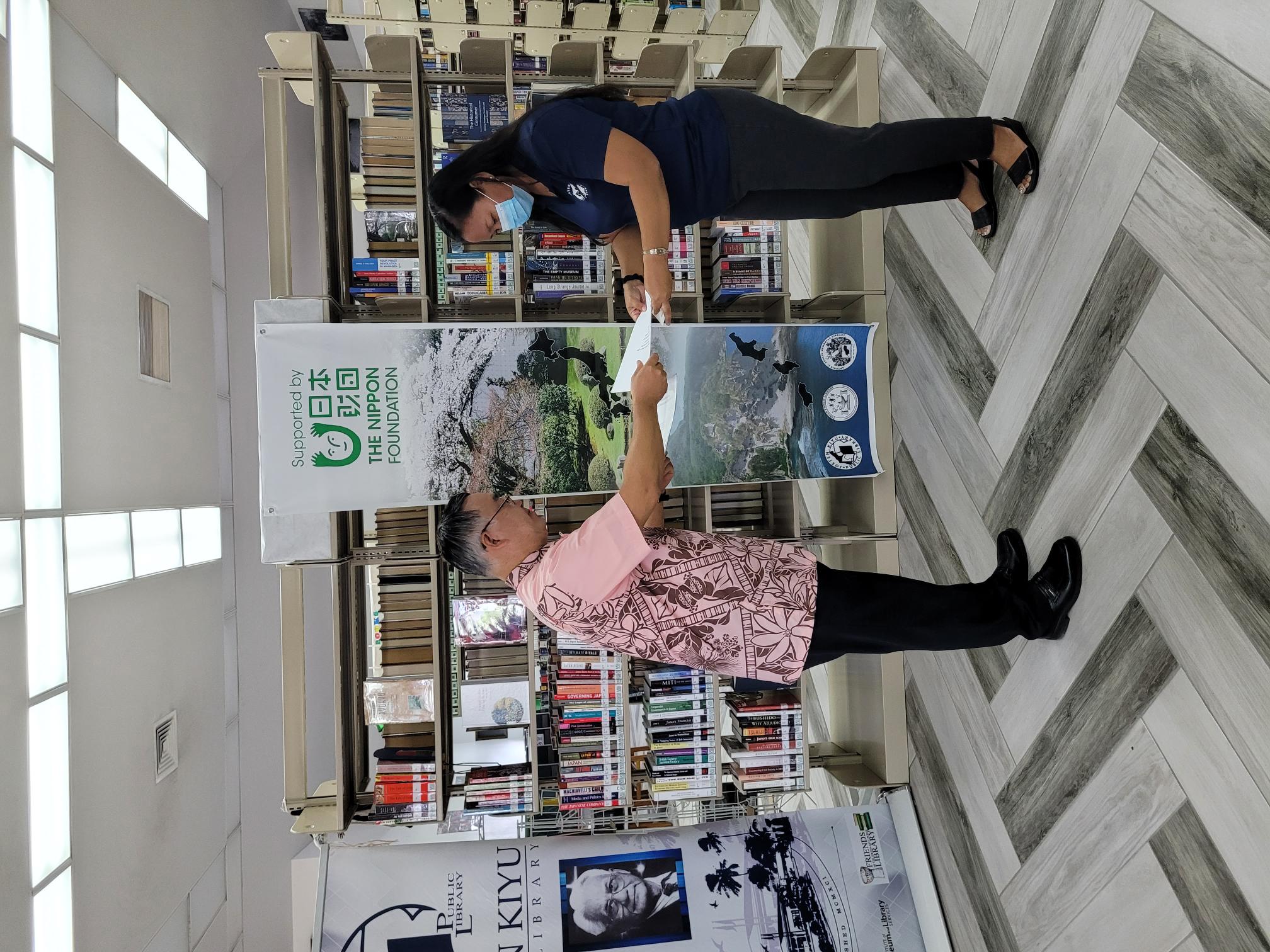 Joeten-Kiyu Public Library Director Erlinda Naputi receives a ceremonial document from Japan Consul Kazuhiko Ono at JKPL on Tuesday.
