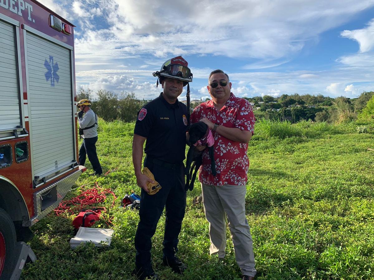 Guam Fire Department Battalion Chief Dean Aguon, left, with Vicente Camacho and his puppy Oro who was rescued after falling 50 feet into a pit in Tamuning on Tuesday.