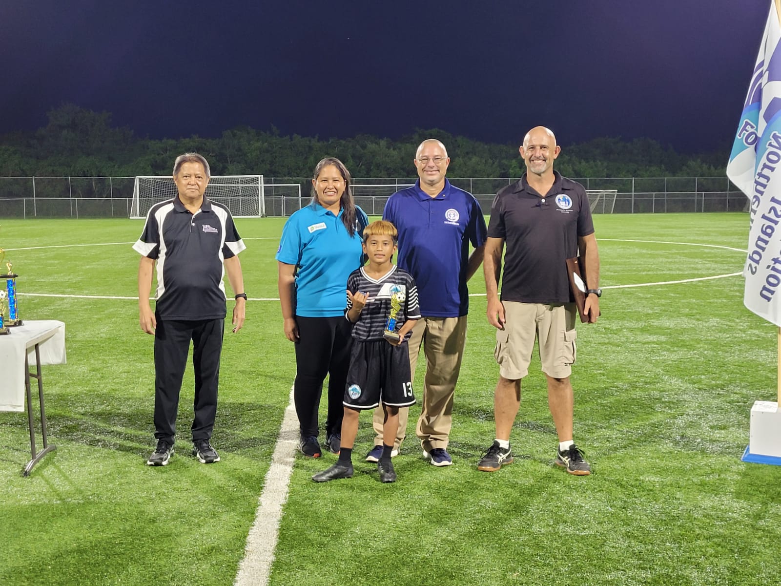 Garapan Elementary School’s Jazzroy Villagomez gestures as he holds the Golden Boot Award in a group photo with NMI Football Association's Ross Zapanta and Catherine Attao-Toves, Board of Education member Greg Borja and Public School System Athletic Program Director Nick Gross during the awards ceremony Wednesday at the NMI Soccer Training Center.