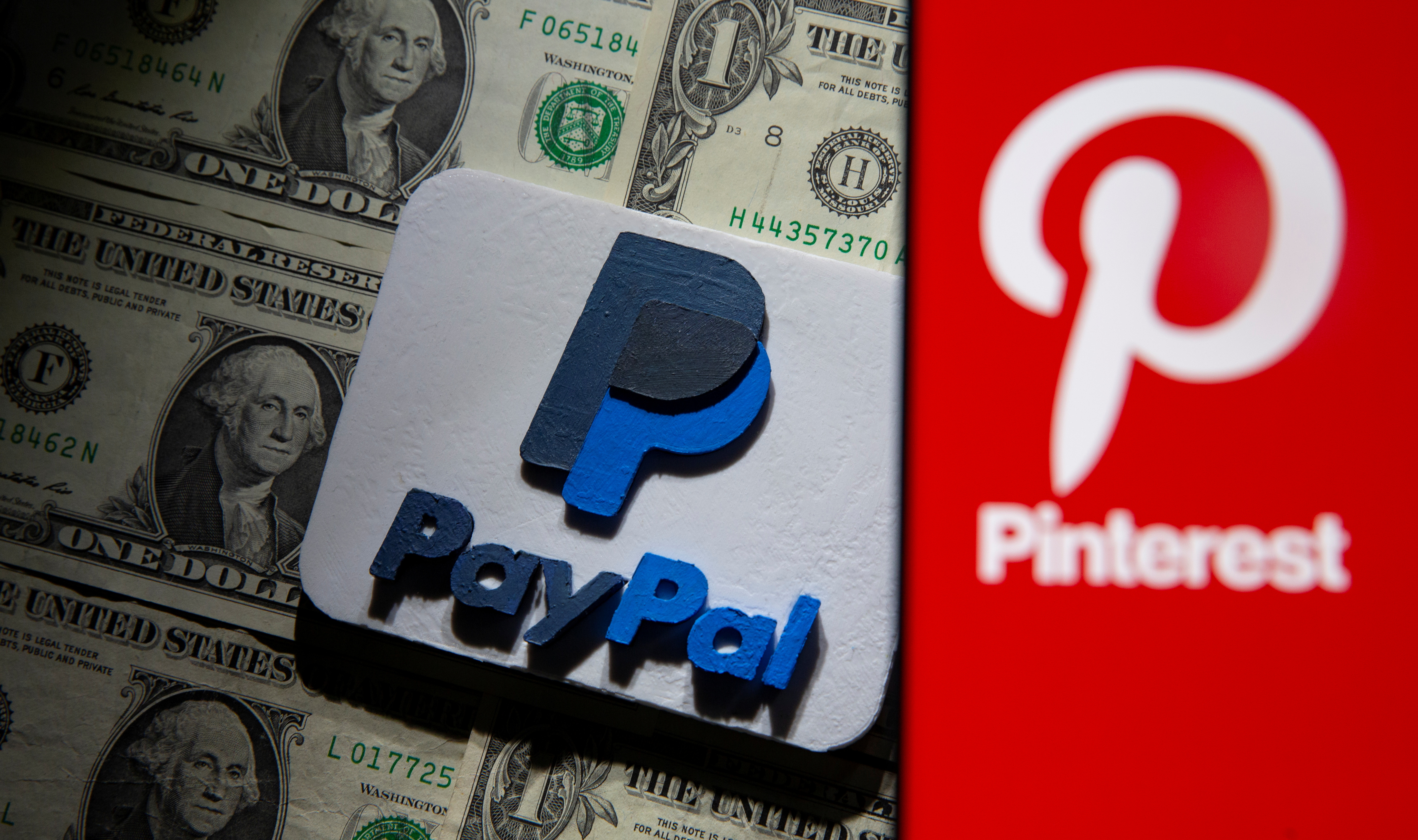 A Pinterest logo is seen on a smartphone placed over U.S. dollar banknotes and a 3D printed PayPal logo in this illustration taken Oct. 20, 2021.