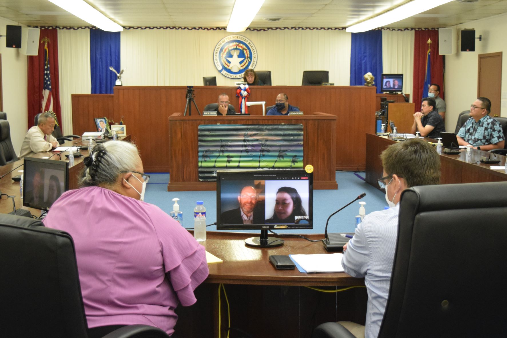 Attorneys Viola Alepuyo, left, and Gil Birnbrich, right, listen to Ross Garber speaks via videocall during the House Judiciary and Governmental Operations meeting on Wednesday in the House chamber.