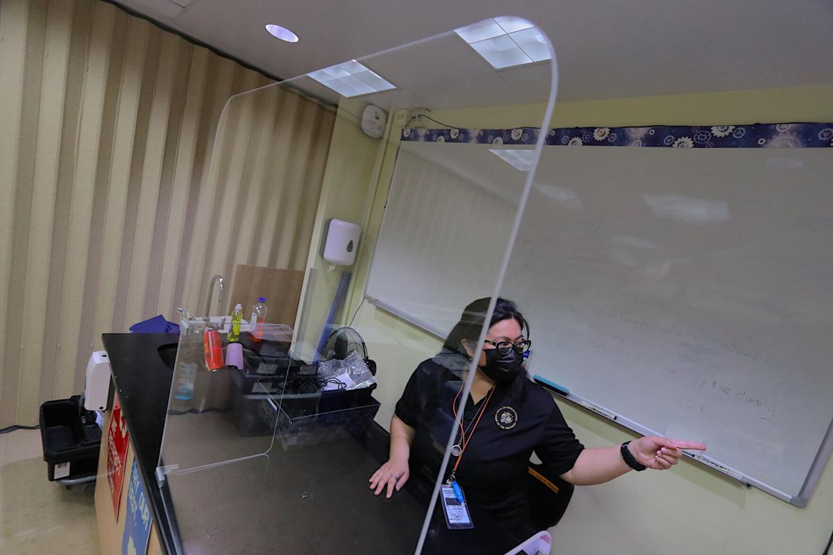 Untalan Middle School robotics teacher Roz Pama conducts a class behind a transparent safety barrier on Monday at the Barrigada campus. Classrooms have been outfitted with temperature check monitors, hand sanitizers, mask supplies and safety barriers, among other equipment. 