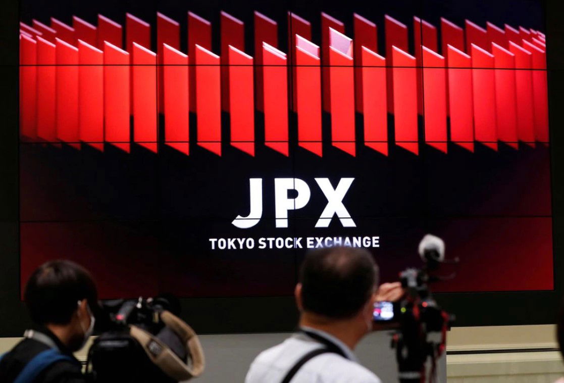 TV camera men wait for the opening of market in front of a large screen showing stock prices at the Tokyo Stock Exchange on Oct. 2, 2020.