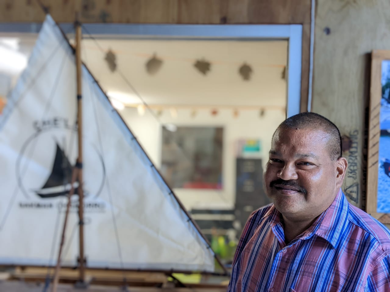 Ross Manglona poses for a photo in front of the 500 Sails office/boatyard in Lower Base.