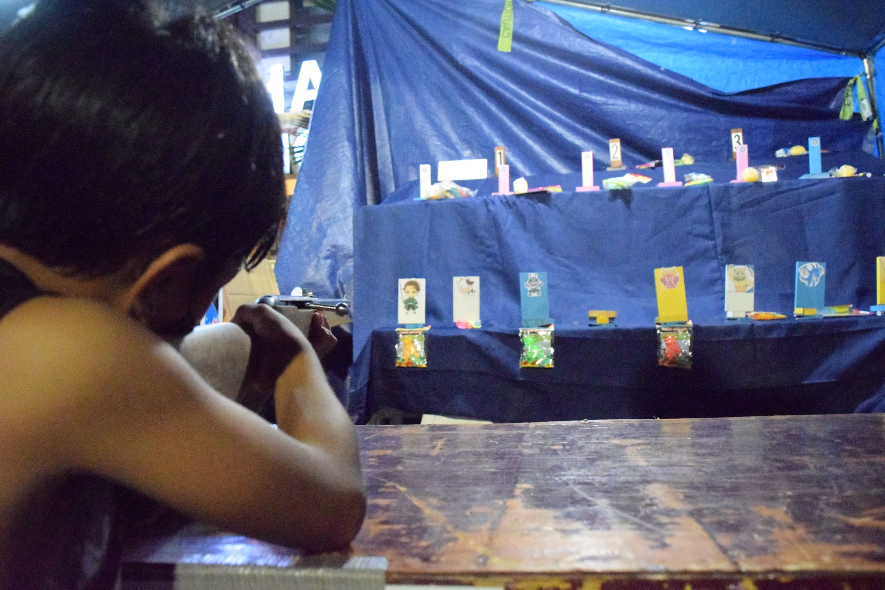 A boy aims a toy rifle at one of prizes at an amusement station during the Japanese Autumn Festival at Paseo De Marianas in Garapan on Saturday.