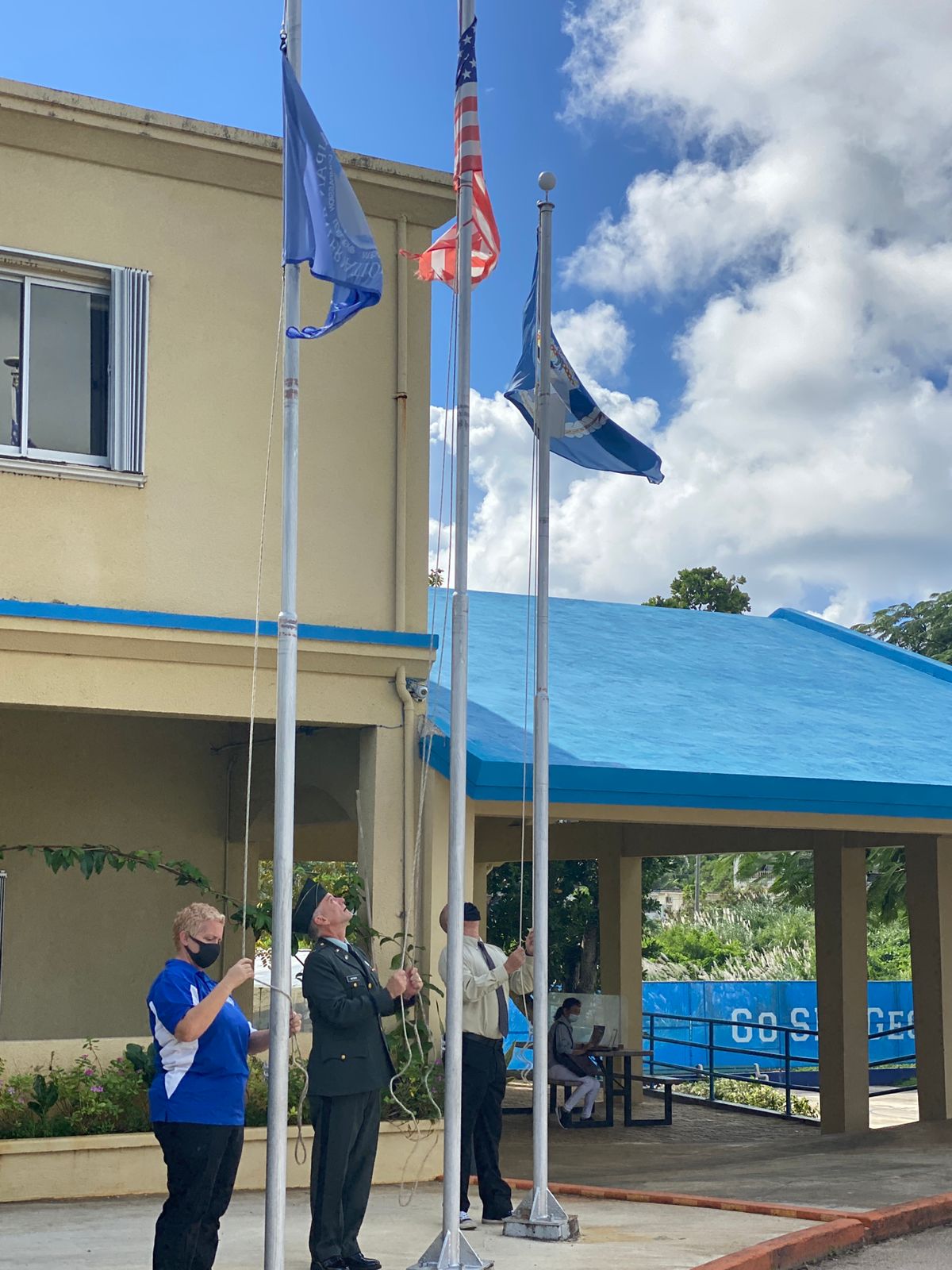 Saipan International School Science teacher April Liske-Clark, a Navy veteran; SIS headmaster Dr. Ron Snyder, an Army veteran;  and Board of Education member and Rotarian Greg Borja, a Marine veteran, lower the school, U.S.  and CNMI flags at SIS on Wednesday.