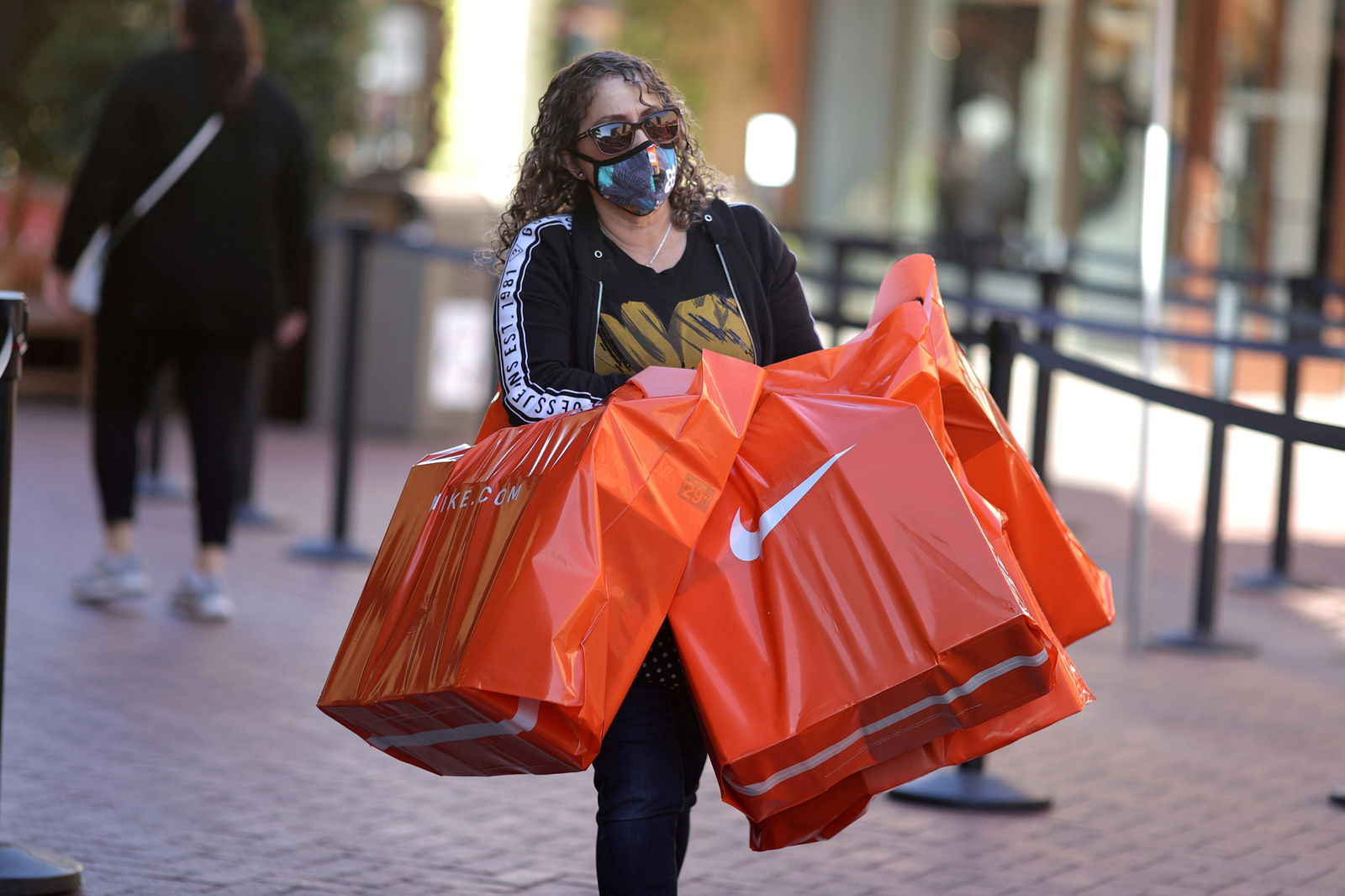 A woman carries Nike shopping bags at the Citadel Outlet mall, as the global outbreak of the coronavirus disease continues, in Commerce, California on Dec. 3, 2020.