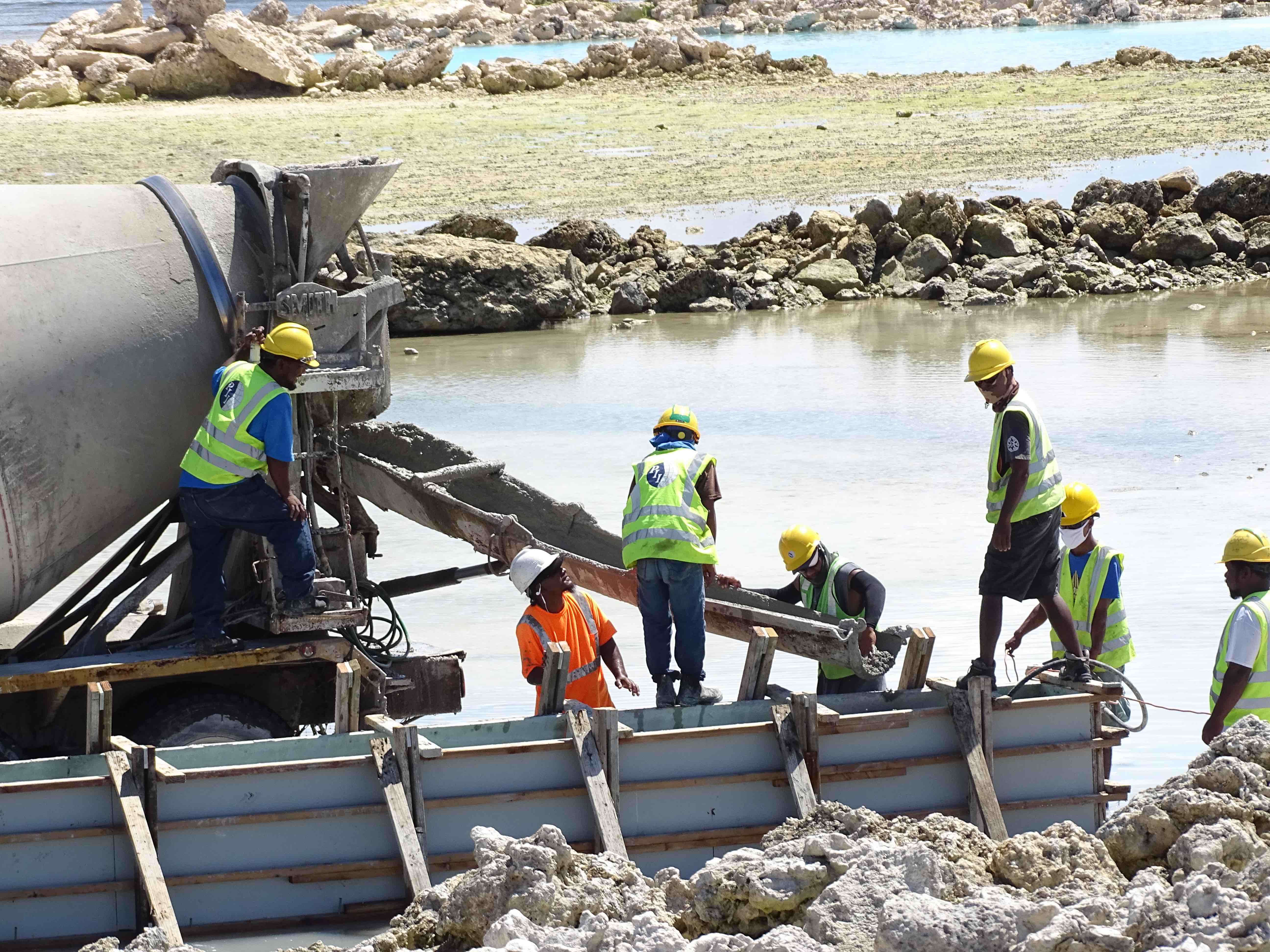 Construction workers with Pacific International Inc. pour concrete for foundations that will support a new track and field and baseball stadium for the upcoming Micronesian Games.