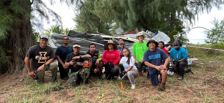 MINA staff and Tasi Watch community rangers gather in front of typhoon-created marine debris in Southern Saipan.