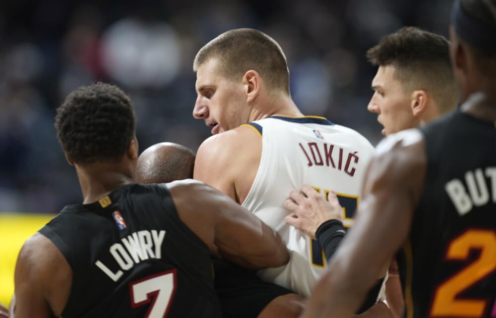 Denver Nuggets center Nikola Jokic, center, is restrained by Miami Heat guards Kyle Lowry, left, and Tyler Herro after knocking over Heat forward Markieff Morris during a scrum in the second half of an NBA basketball game Monday in Denver. 