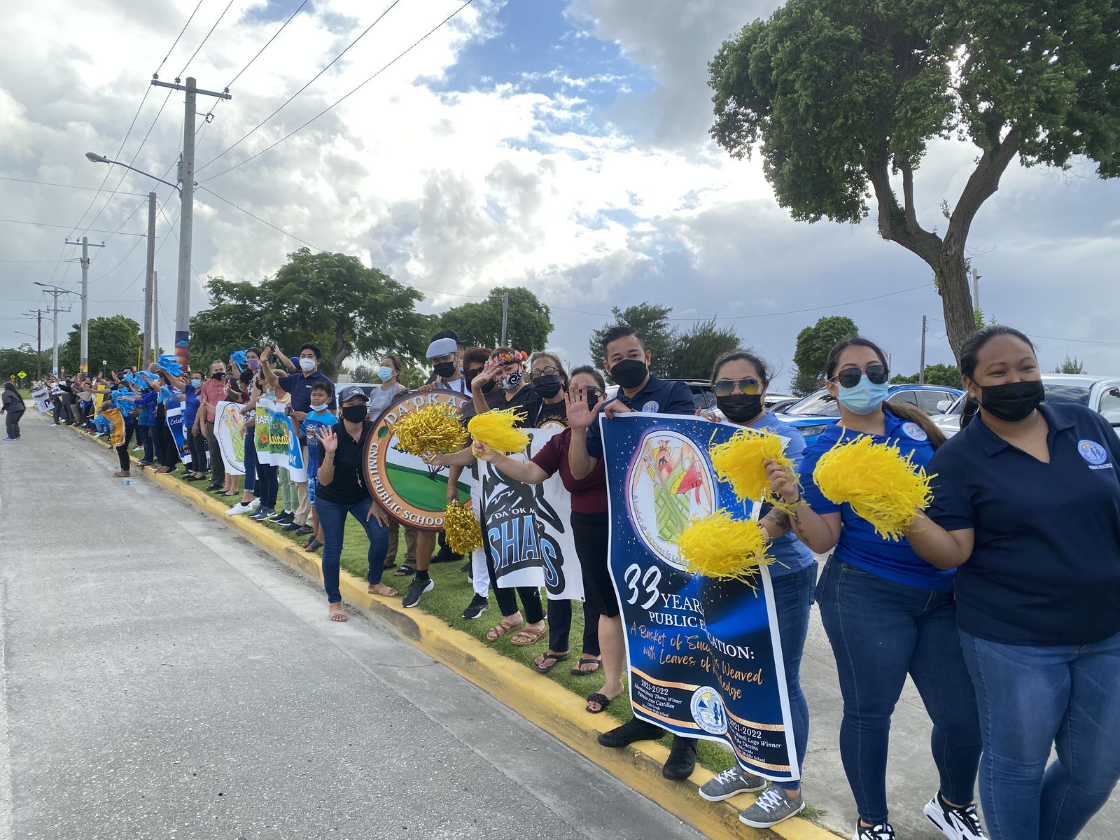 PSS employees hold banners and pompoms during the road side waving event.