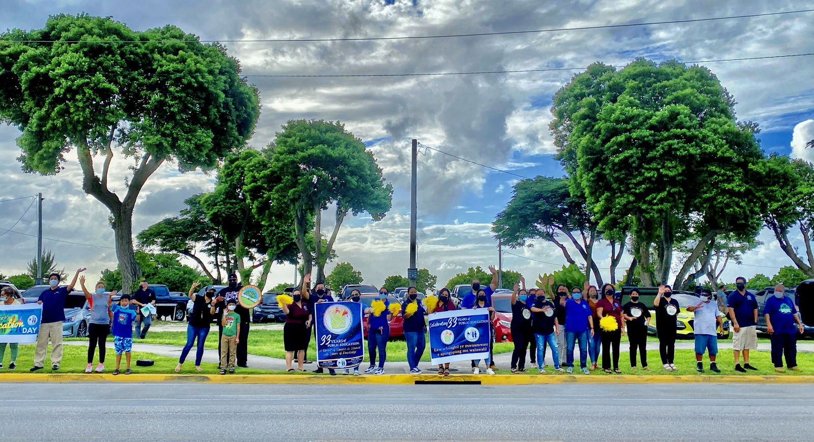 Saipan school and PSS central office personnel wave at motorists at Garapan Fishing Base on Beach Road.