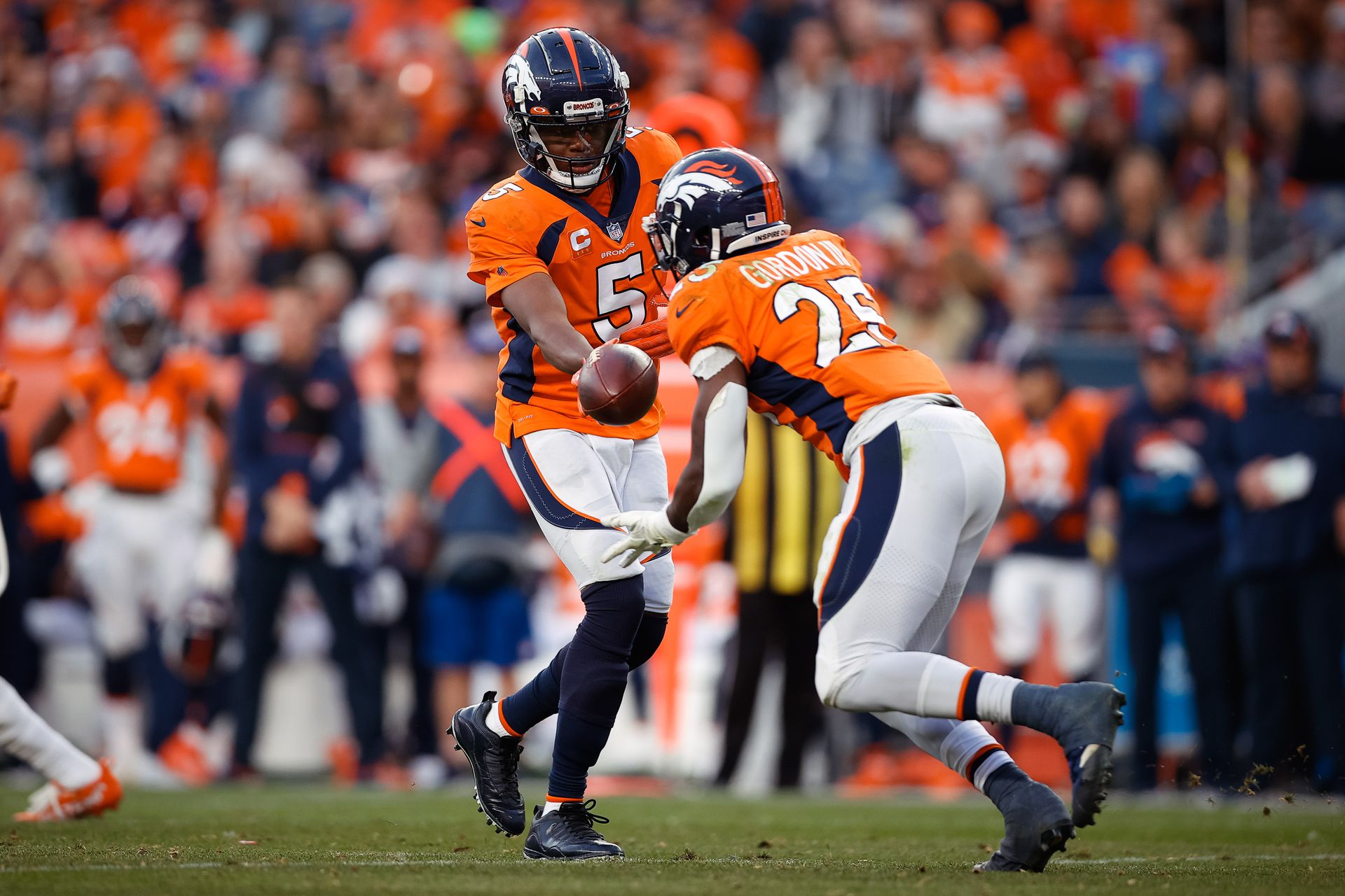 Denver Broncos quarterback Teddy Bridgewater (5) hands the ball off to running back Melvin Gordon III (25) in the third quarter against the Los Angeles Chargers at Empower Field at Mile High in Denver, Colorado on Nov. 28, 2021.
