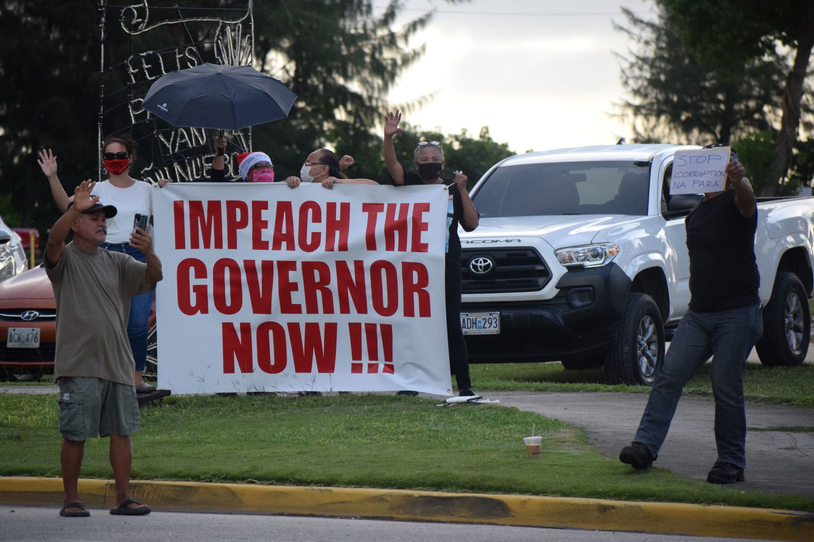 Residents hold a big banner during a demonstration calling for the governor’s impeachment at the Garapan Fishing Base on Tuesday.