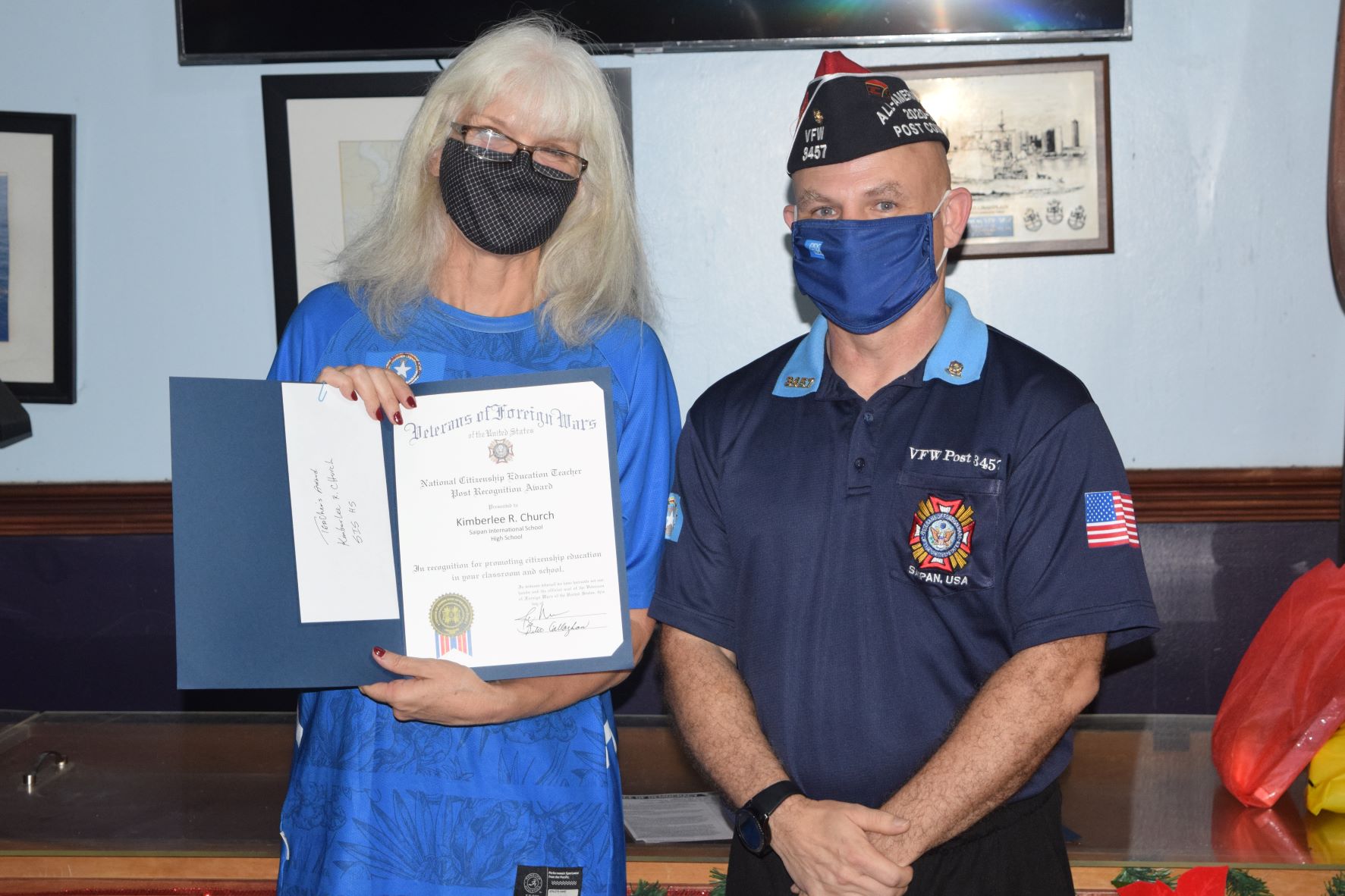 Saipan International School teacher Kimberlee Church holds her award as she poses for a photo with Veterans of Foreign Wars 3457 Post Commander Capt. Joey McDoulett at the VFW Post 345 in Garapan on Friday.