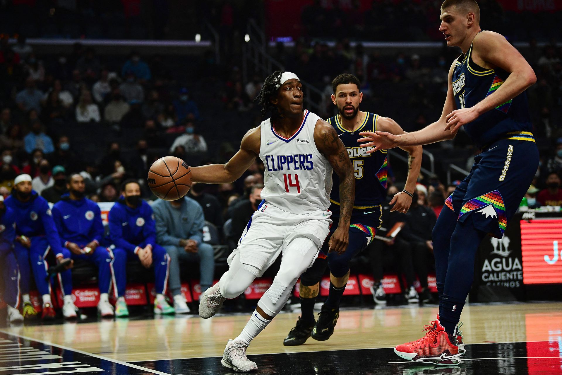 Los Angeles Clippers guard Terance Mann (14) moves the ball against Denver Nuggets guard Austin Rivers (25) and center Nikola Jokic (15) during the first half at Crypto.com Arena in Los Angeles, California on Dec. 26, 2021.