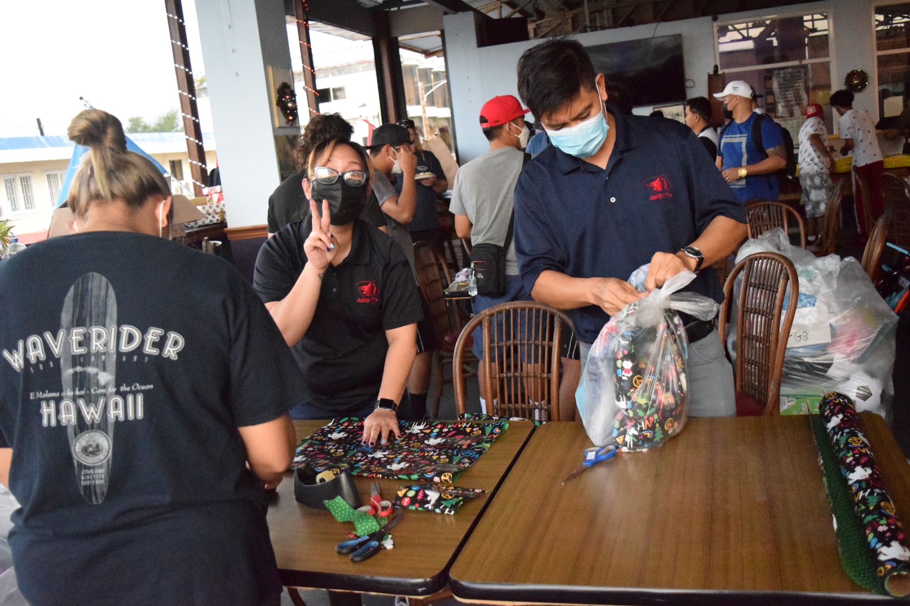 Ambyth Shipping administrative supervisor Jovie Villacrusis, center, manager Marlon Punzalan, right, and maintenance helper Mary Jane Molina, back to the camera, wrap Christmas gifts for the annual Guma Esperansa Christmas toy donation drive at the Veterans of Foreign Wars Post 3457 in Garapan on Tuesday.