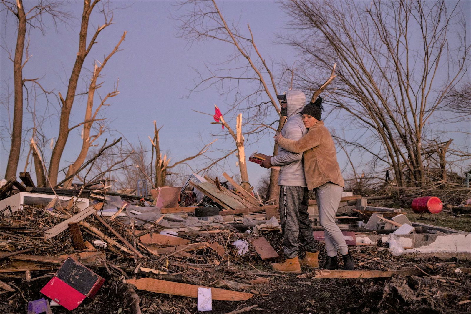 Bridget Avery embraces her friend Derrick Starks after helping him retrieve family mementos and a photo album from the destroyed home of Starks' uncle, in the aftermath of a tornado in Mayfield, Kentucky, Dec. 12, 2021.