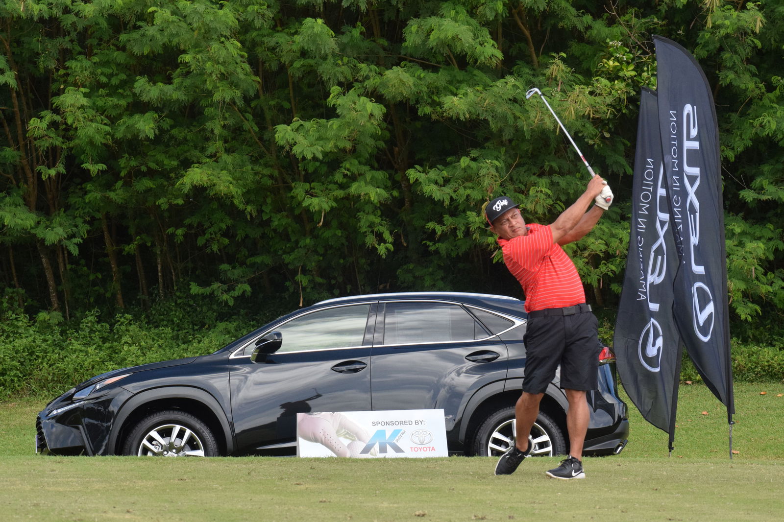 JJ Atalig tees off next to a Hole-in-One prize, a brand new Lexus from Atkins Kroll, on Hole No. 13 at Laolao Bay Golf & Resort Saturday.