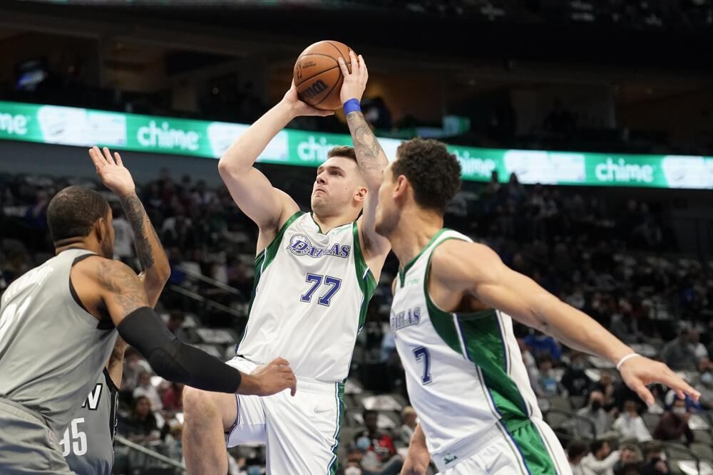 Dallas Mavericks guard Luka Doncic (77) takes a shot as Brooklyn Nets' LaMarcus Aldridge, left, and Dwight Powell (7) look on in the first half of an NBA basketball game in Dallas, Tuesday.
