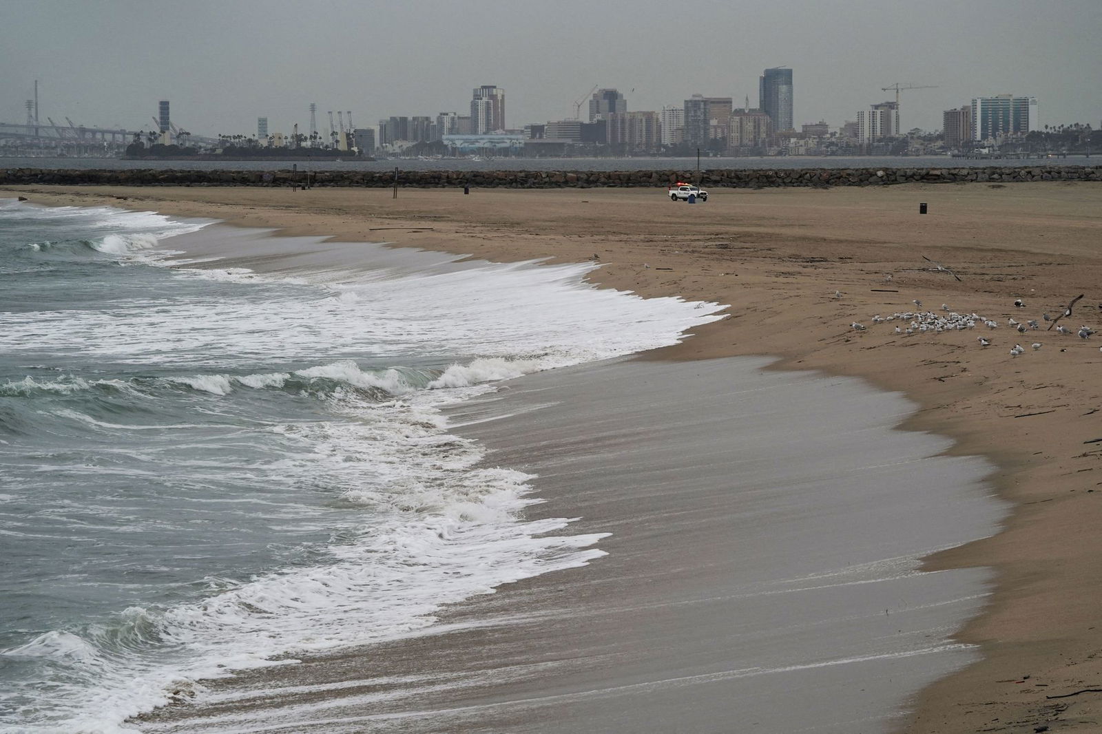 A general view of the Long Beach at a distance as a City of Seal Beach lifeguard truck patrols a beach closed a tsunami advisory was issued following an underwater volcano eruption over 8,500 km (around 5,300 miles) away in Seal Beach, California, Jan. 15, 2022.