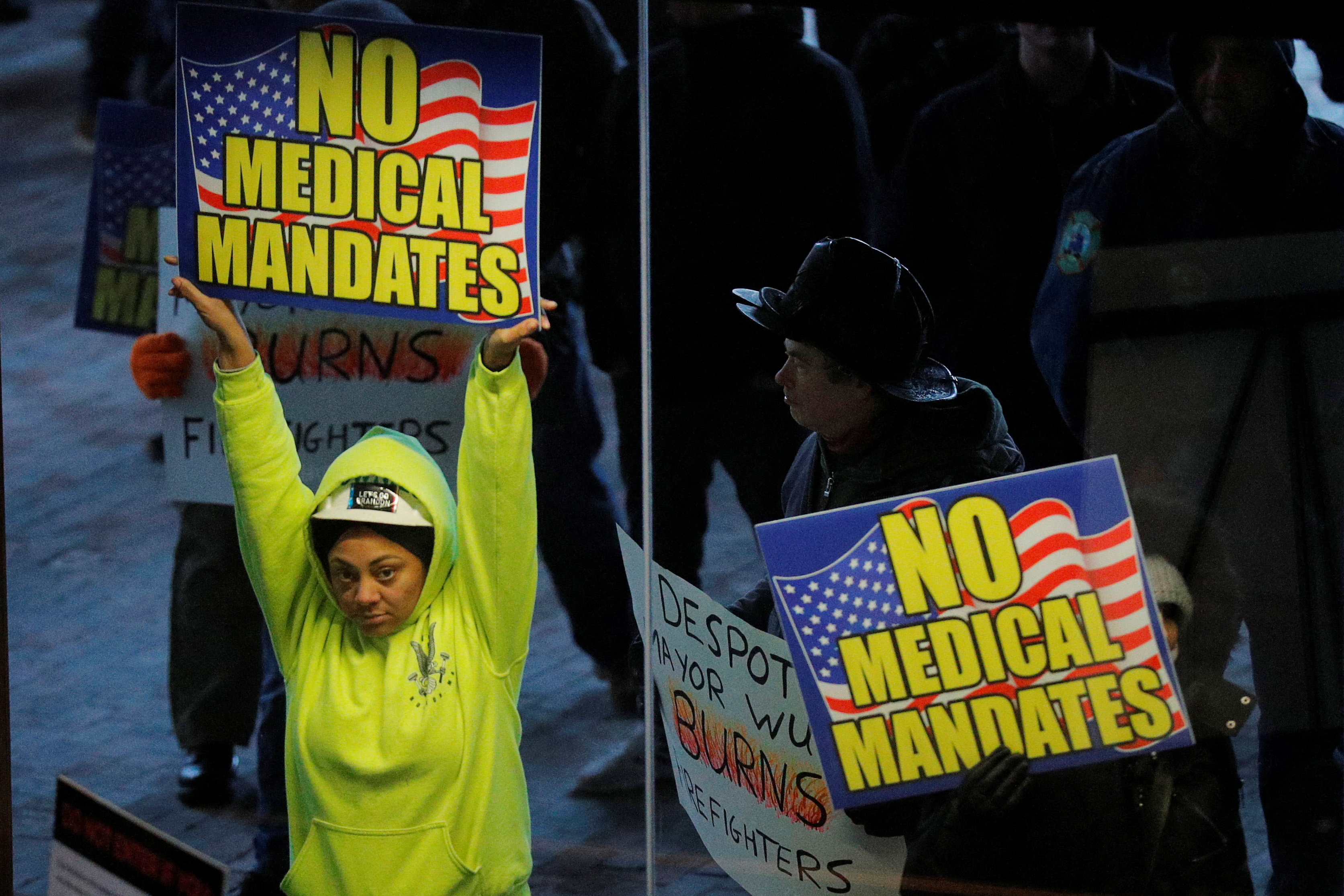 Demonstrators protesting against coronavirus disease vaccine mandates and other mitigation measures, stand outside the windows of the City Hall in Boston, Massachusetts, Jan. 3, 2022.