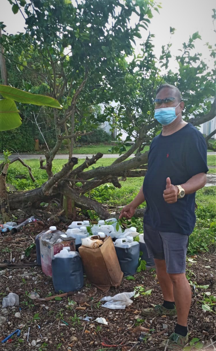 Community volunteer Max Aguon points to containers filled with used cooking oil that were  dumped on private property in Chalan Kanoa District 3 on Monday.