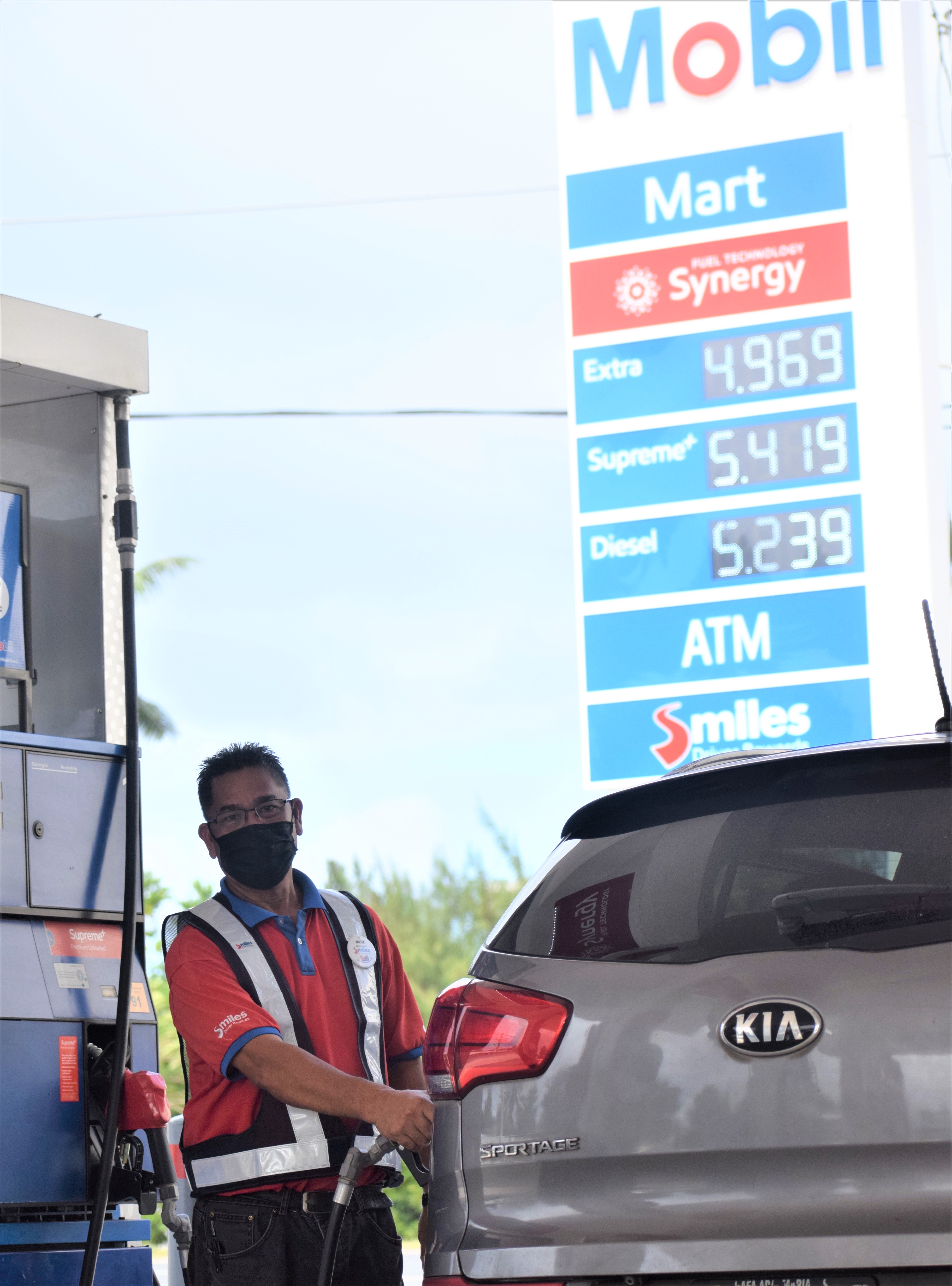 Mobil Oil Susupe filling station attendant Renato Noble serves a customer on Thursday.