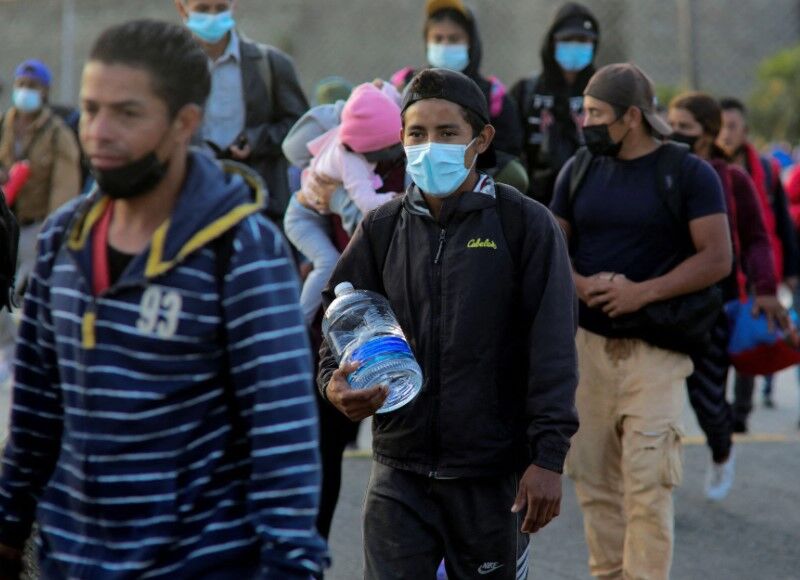 Migrants stand in the street as a caravan of migrants from Central America sets off for the United States, in San Pedro Sula, Honduras, Jan. 14, 2022.