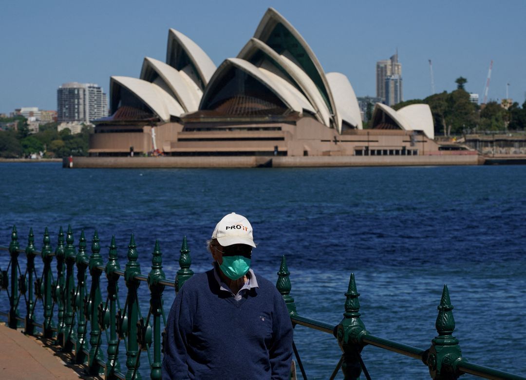 A person wearing a face mask walks along the harbor waterfront across from the Sydney Opera House during a lockdown to curb the spread of the coronavirus disease in Sydney, Australia, Oct. 6, 2021.